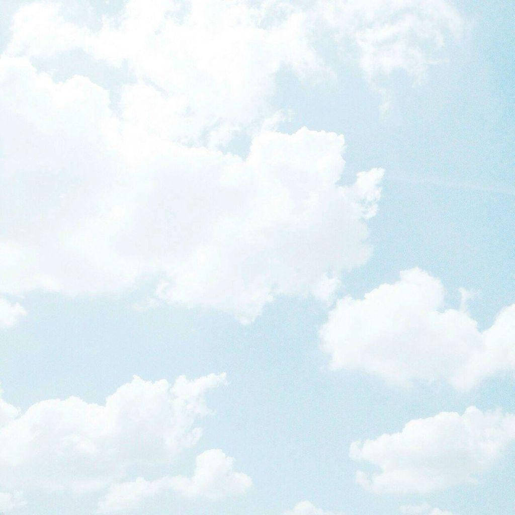 淡藍色天空，帶有柔軟白雲和復古菲林顆粒紋理。