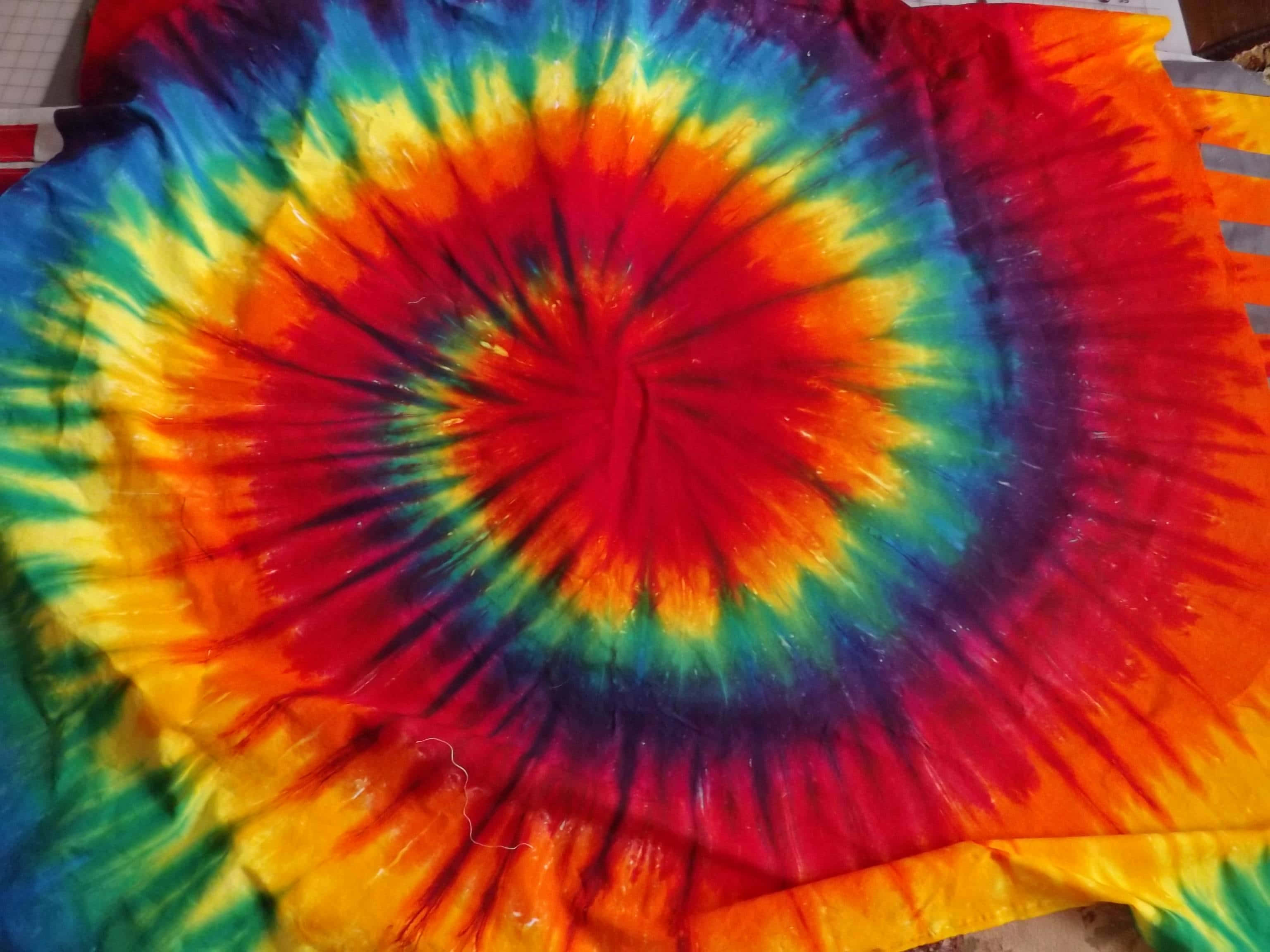 在自然中享受寧靜喜悅的嬉皮士 壁紙 — 充滿活力的彩虹螺旋紮染布料從火紅的中心向外輻射，帶有橙色、黃色、綠色和藍色的鮮明條紋。