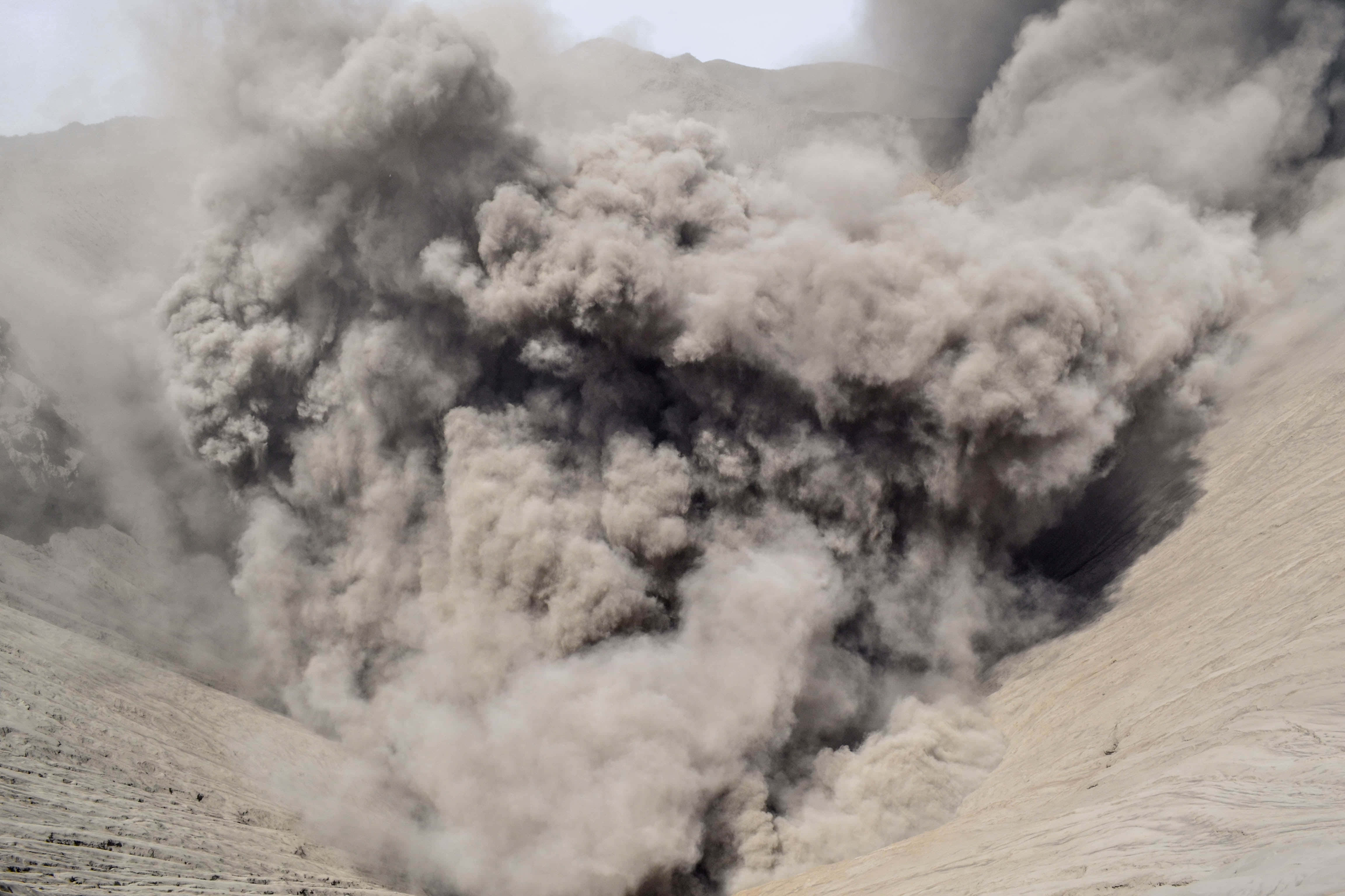 Dust 桌布 壁紙 — 在蒼白的天空映襯下，巨大的火山灰和煙霧柱從火山口猛烈噴發。