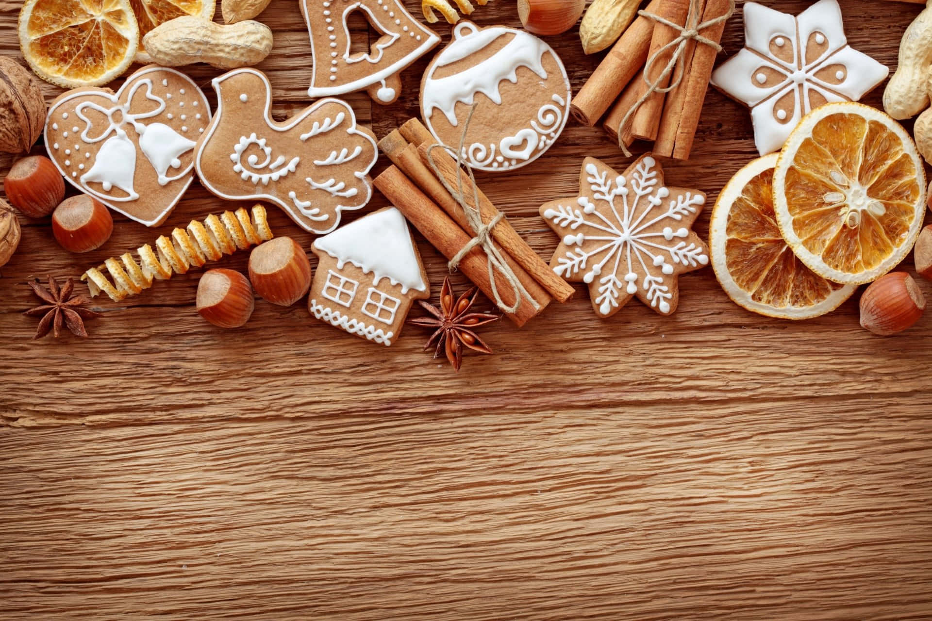 Gingerbread 桌布 壁紙 — 在質樸的木質表面上，節日擺設了薑餅曲奇、雪花、肉桂棒和乾橙。