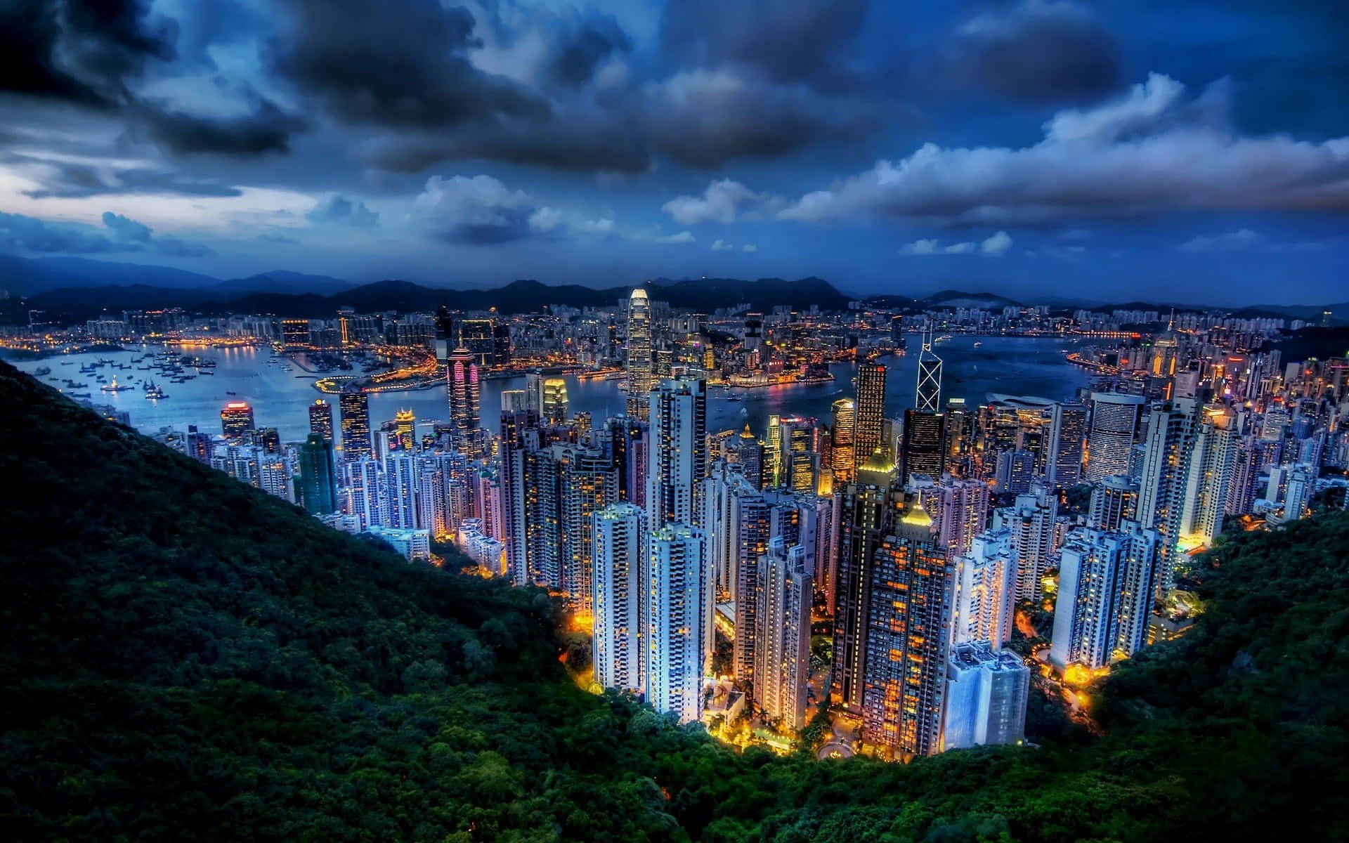 香港黃昏天際線，燈火通明的建築和港灣船隻。
