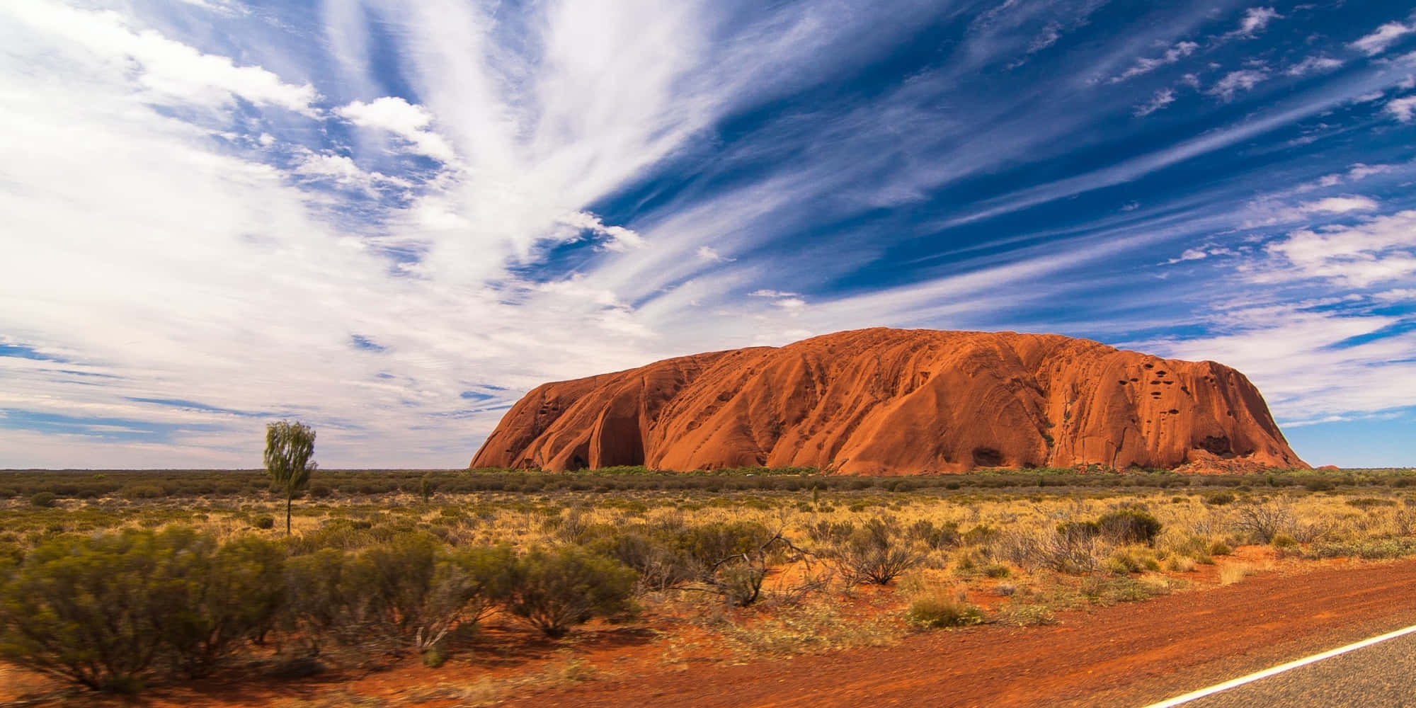 Australia 桌布 壁紙 — 在遙遠的澳洲內陸，一片巨大的紅色岩層在戲劇性的藍天白雲下巍然聳立。