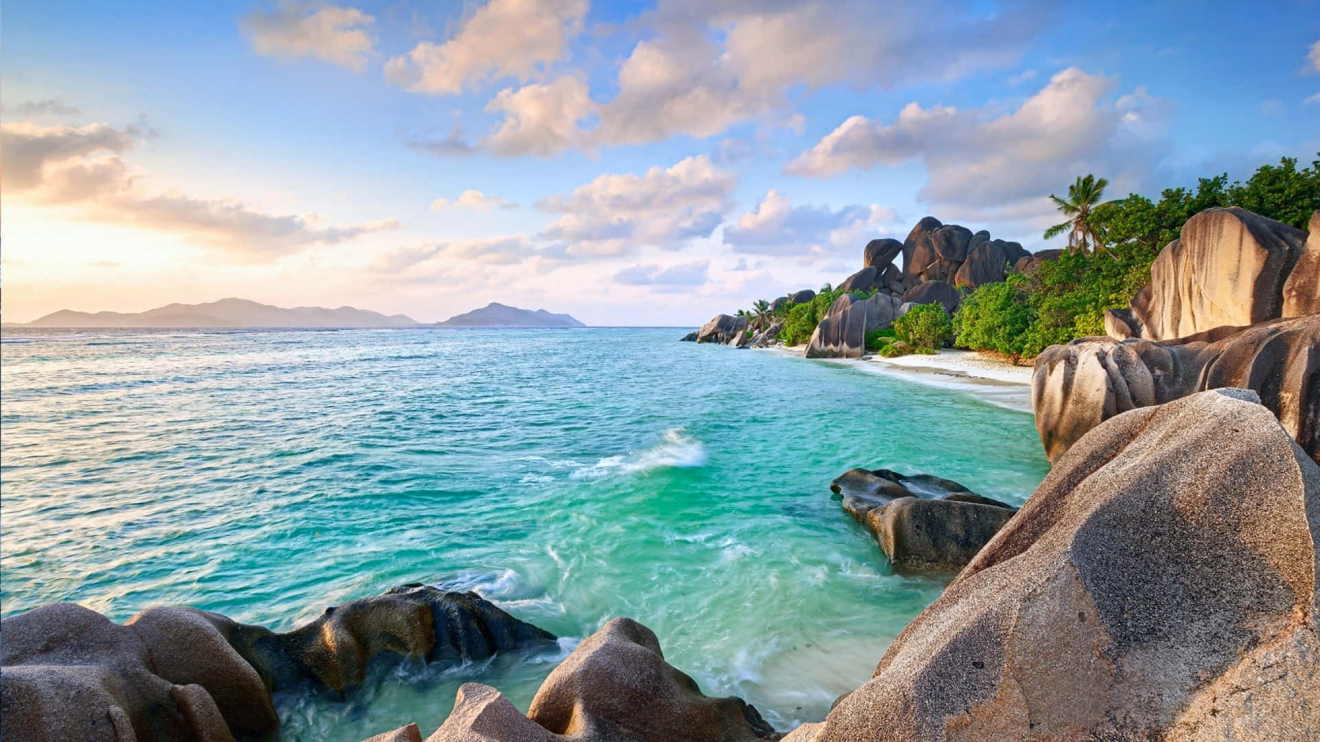 Beach Photography 桌布 壁紙 — 在部分多雲的天空下，碧綠的海水拍打著偏遠熱帶海灘上的巨大花崗岩巨石。
