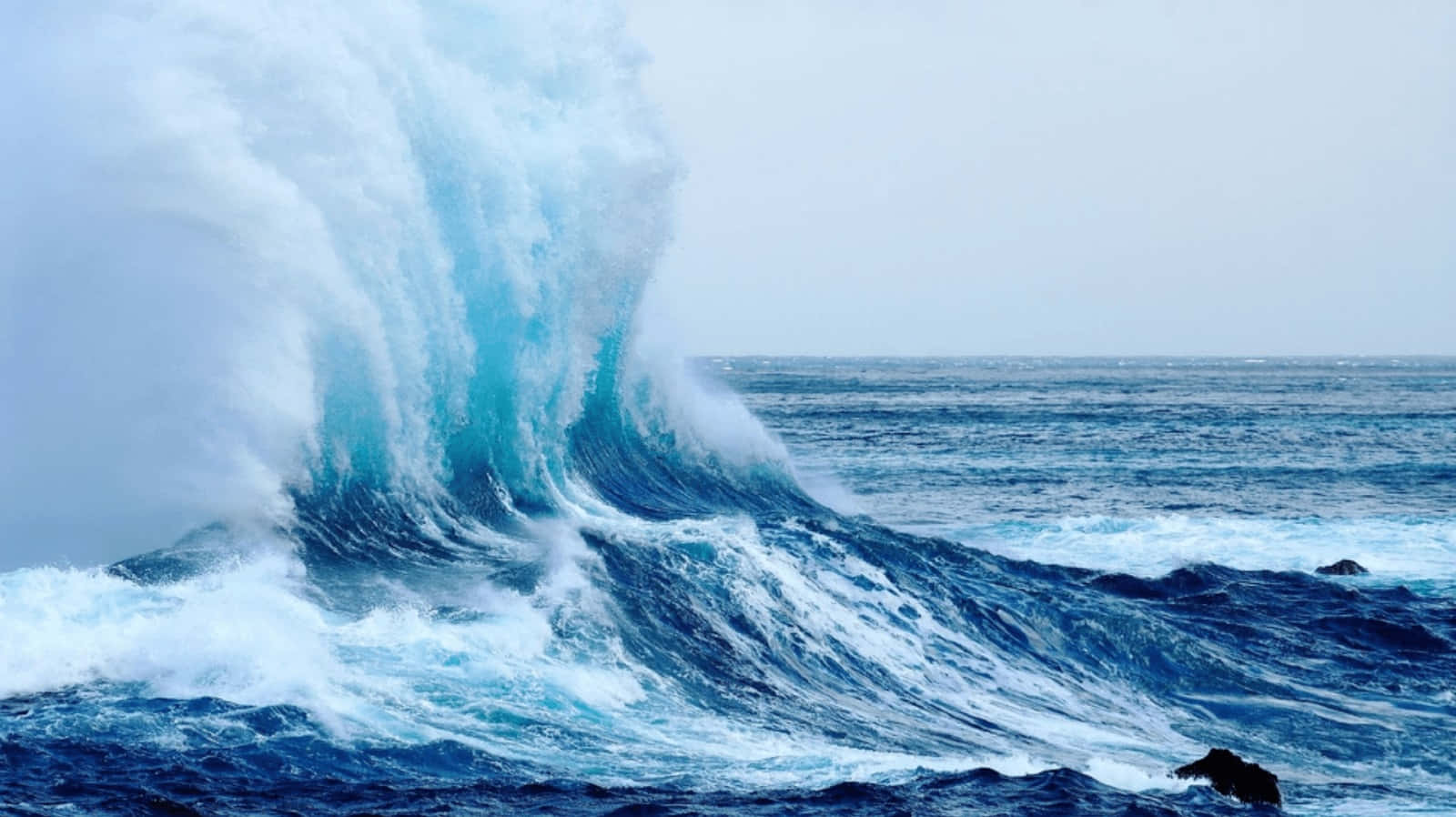 waves 桌布 壁紙 — 在陰天之下，巨大的藍綠色海浪帶著白色泡沫猛烈拍打著暴風雨中的海洋。