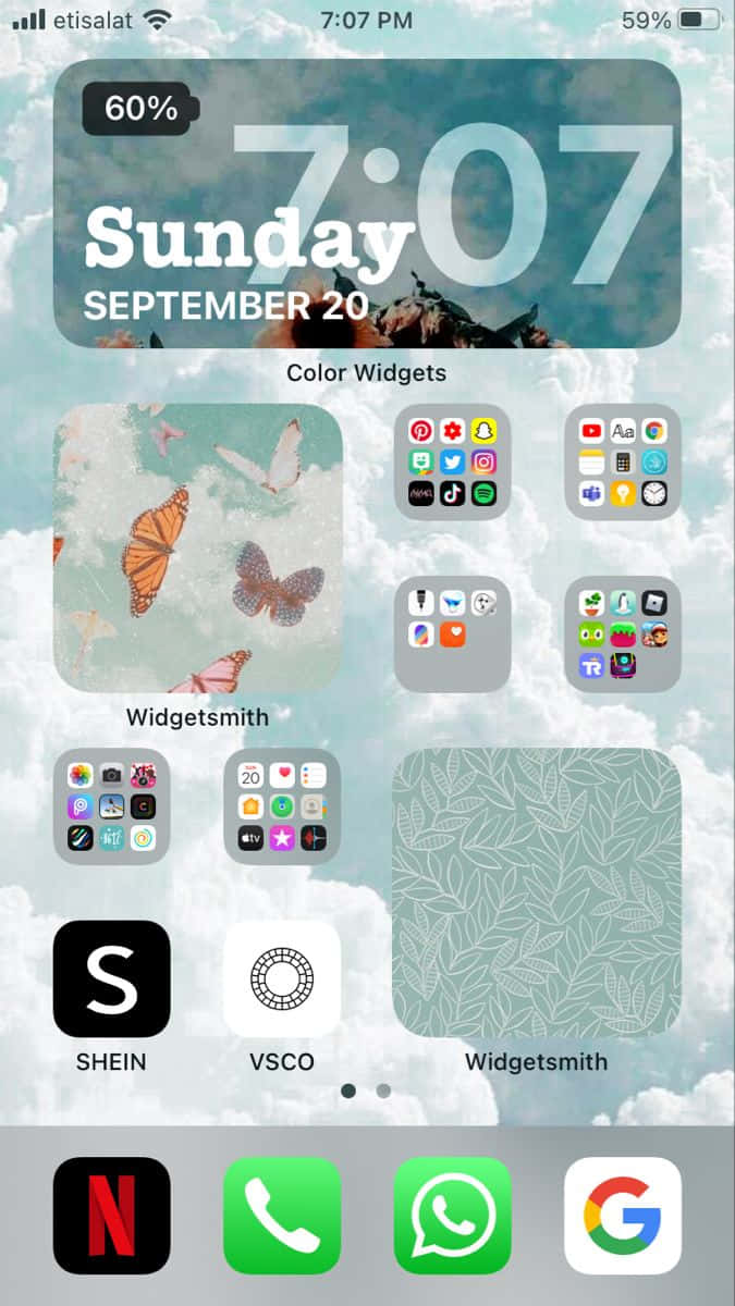 iPhone風格壁紙 桌布 壁紙 — 在陰天天空下，帶有蝴蝶壁紙和應用程式小工具的 iPhone 主屏幕。