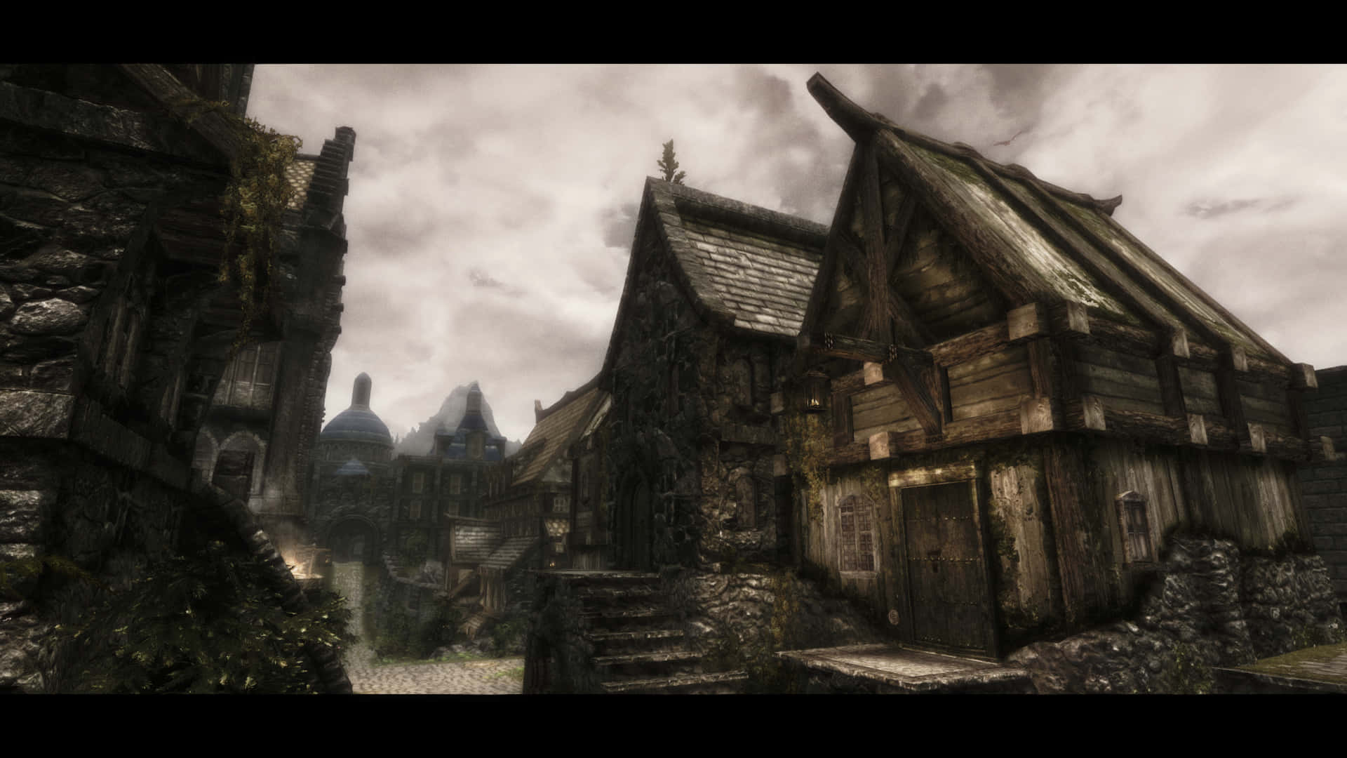 Skyrim Solitude 桌布 壁紙 — 在陰沉多雲的天空下，一個迷霧籠罩的中世紀村莊中的古老石頭和木頭建築。