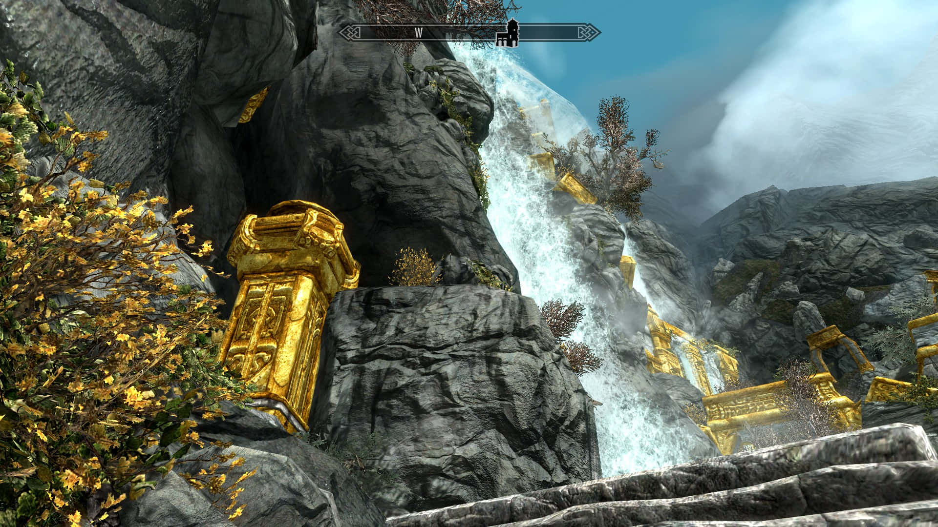 Skyrim Markarth 桌布 壁紙 — 在陰雲密布的天空下，雄偉的瀑布從崎嶇的懸崖上傾瀉而下，旁邊是金色的古老遺跡和秋日樹葉。