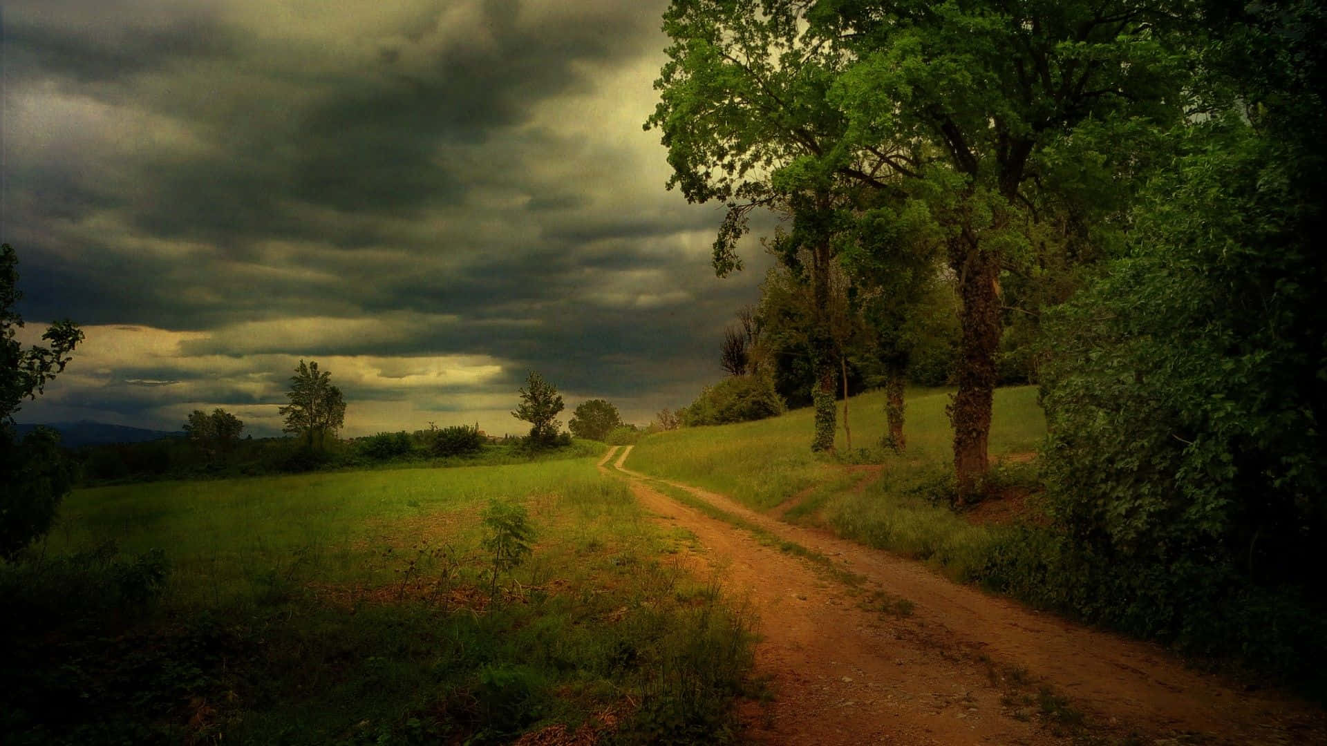 蜿蜒的泥土小徑穿過綠色田野，上方是暴風雨天空和烏雲。