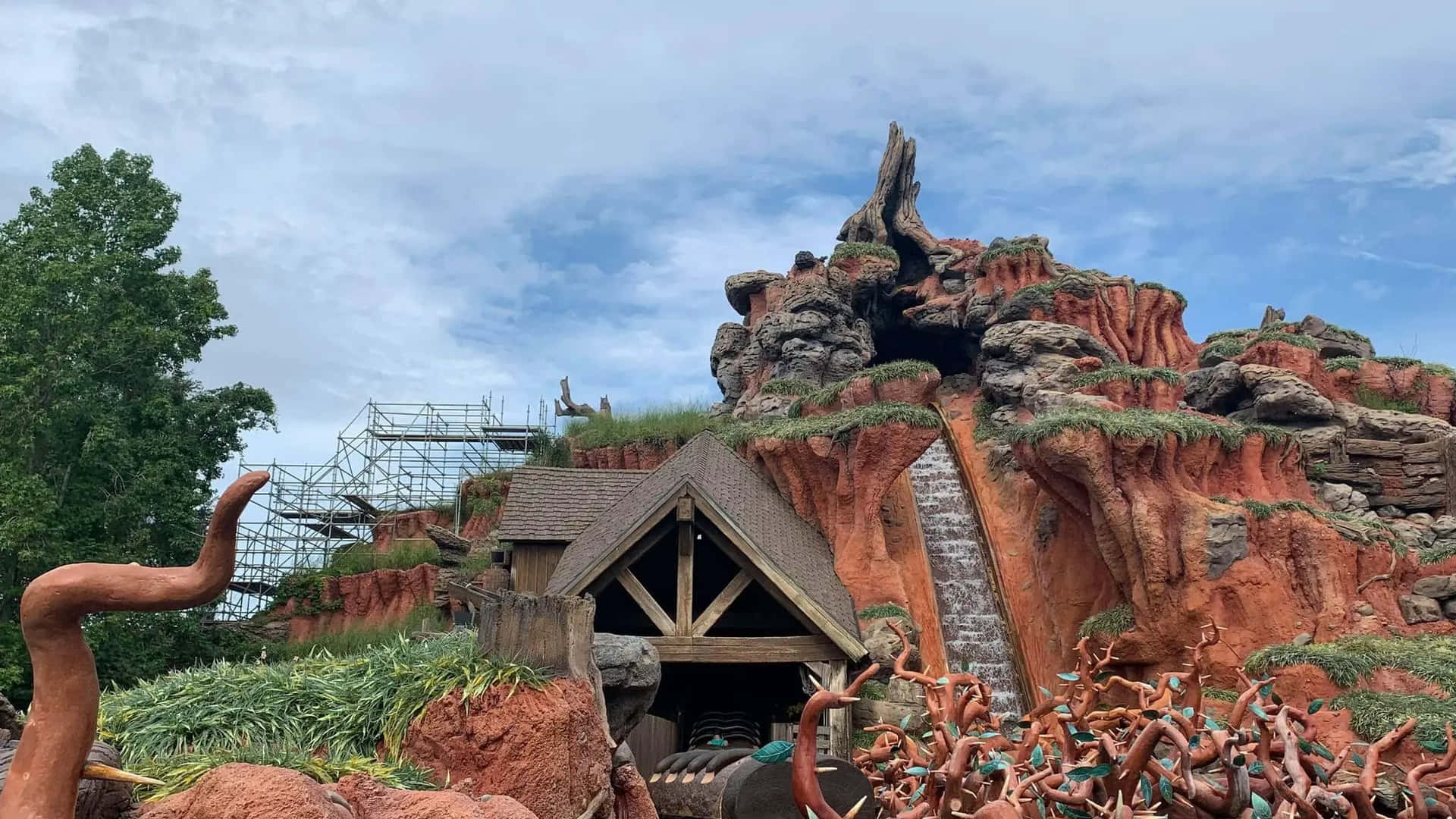 紅色岩石峽谷中的質樸木建築，有瀑布和雕塑般的樹木。
