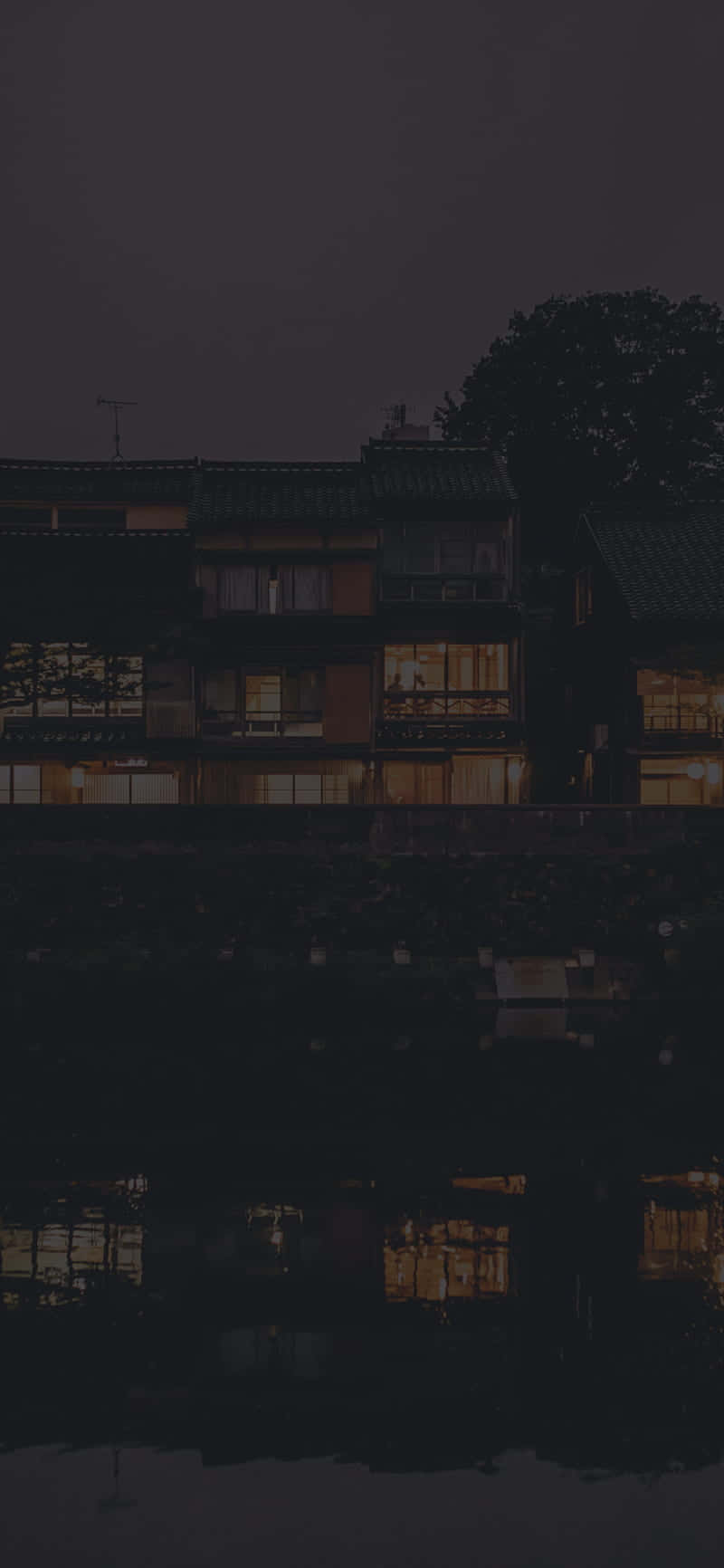 夜晚的傳統房屋，溫暖的燈光倒映在水中