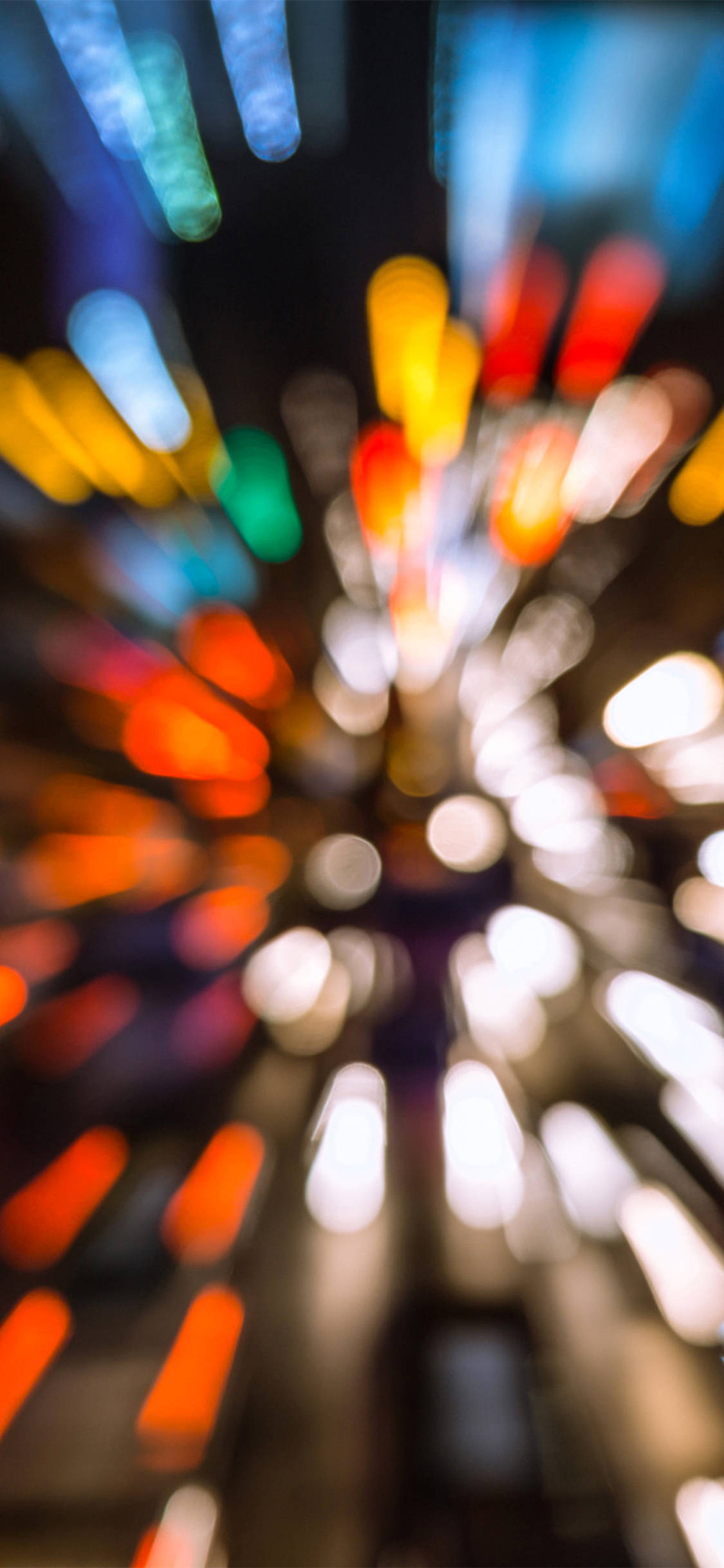 speeding car 桌布 壁紙 — 在黑暗夜空背景下，從中心點向外輻射的充滿活力的抽象模糊彩色城市燈光。