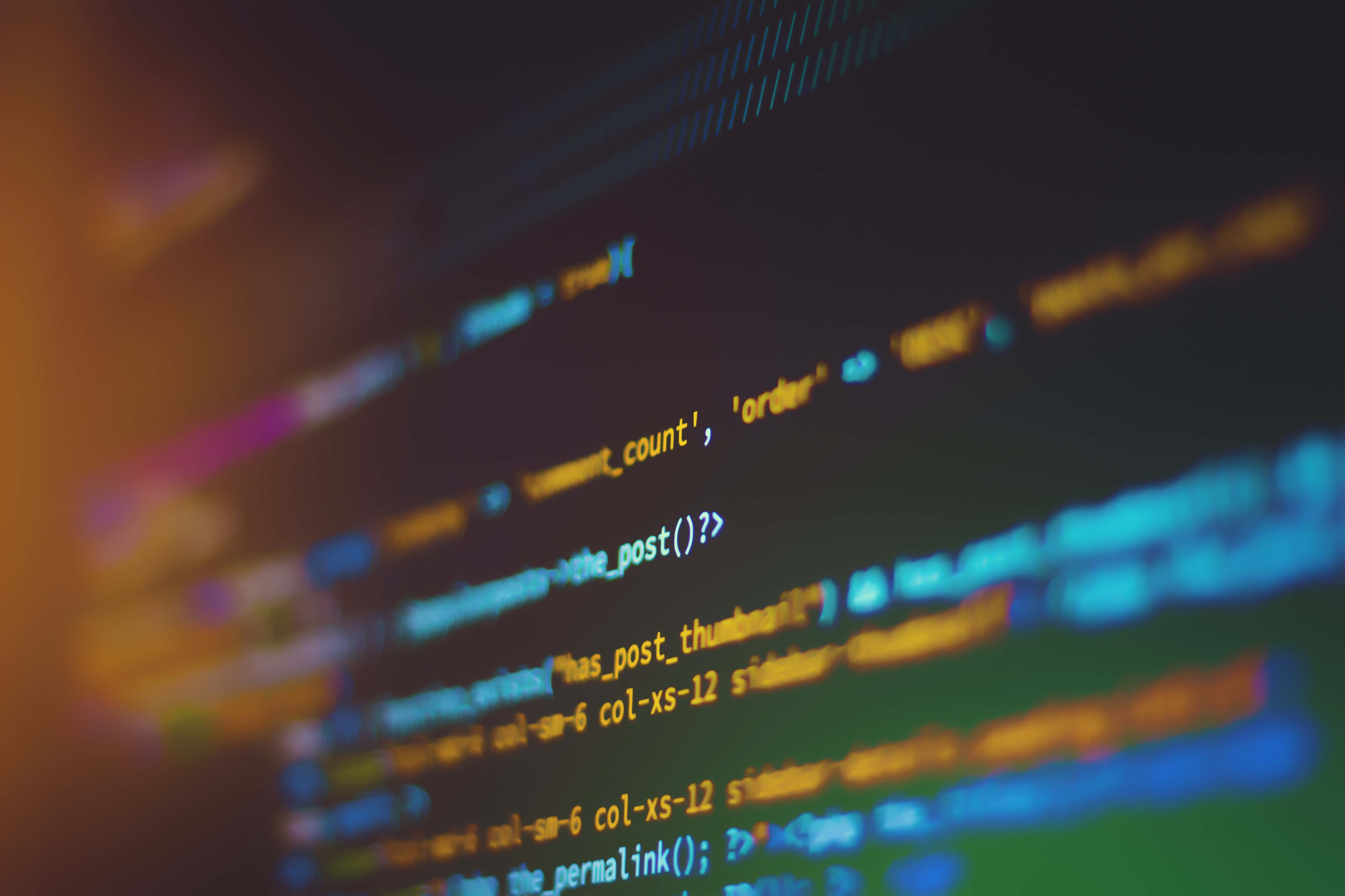 4K Programming 桌布 壁紙 — 在黑暗屏幕上模糊的發光代碼線條，帶有溫暖的橙色和冷藍色亮點。