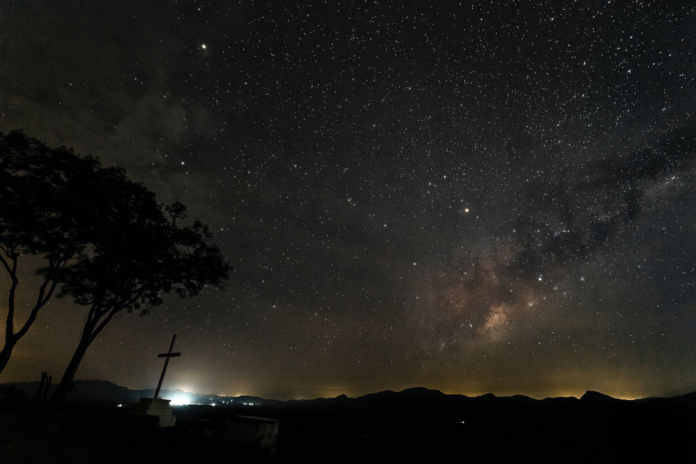 星星 桌布 壁紙 — 在黑暗的天穹下，銀河拱起於剪影樹木和遠處山丘之上的星空夜空。