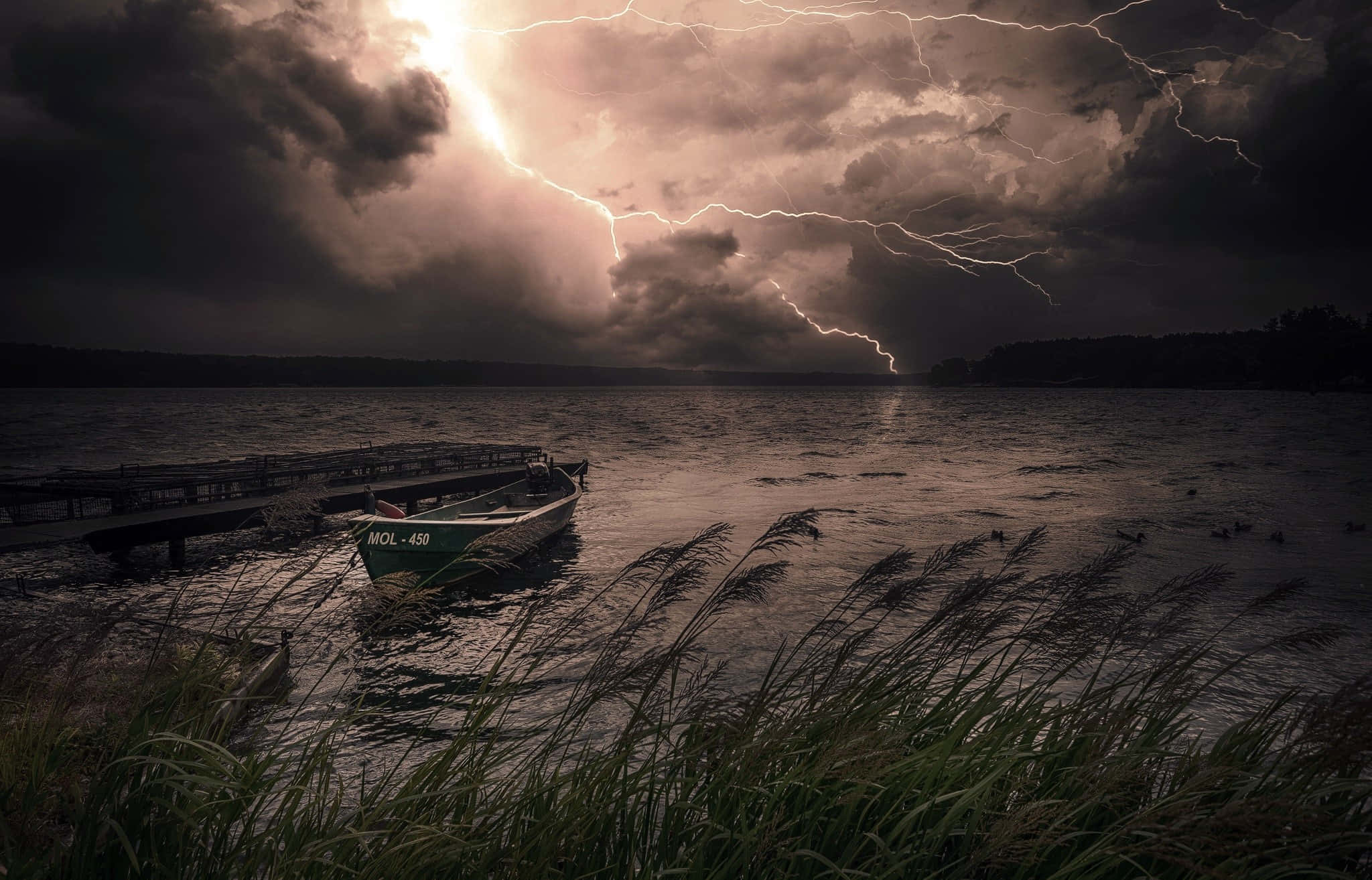 Dark Storm 桌布 壁紙 — 在黑暗的天空下，鋸齒狀閃電照亮暴風雨的湖泊，一艘孤獨的綠色划艇停靠在碼頭。