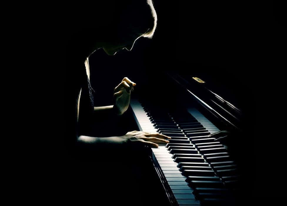 Musical 桌布 壁紙 — 在黑暗的房間中，鋼琴家的剪影在戲劇性的聚光燈下彈奏三角鋼琴。