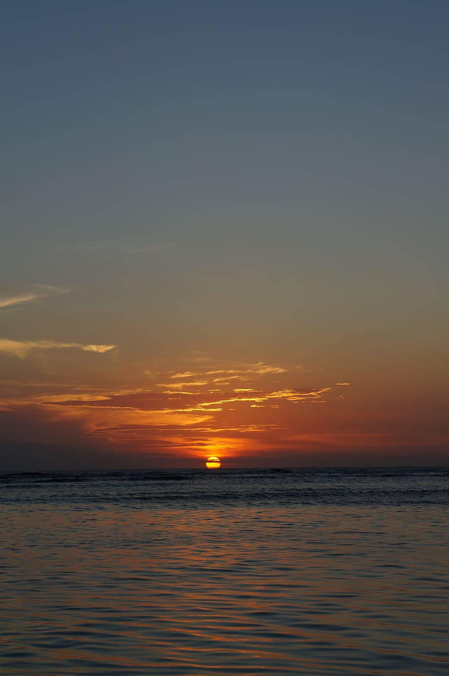 平靜海面上的日落，溫暖的橙色和藍色天空