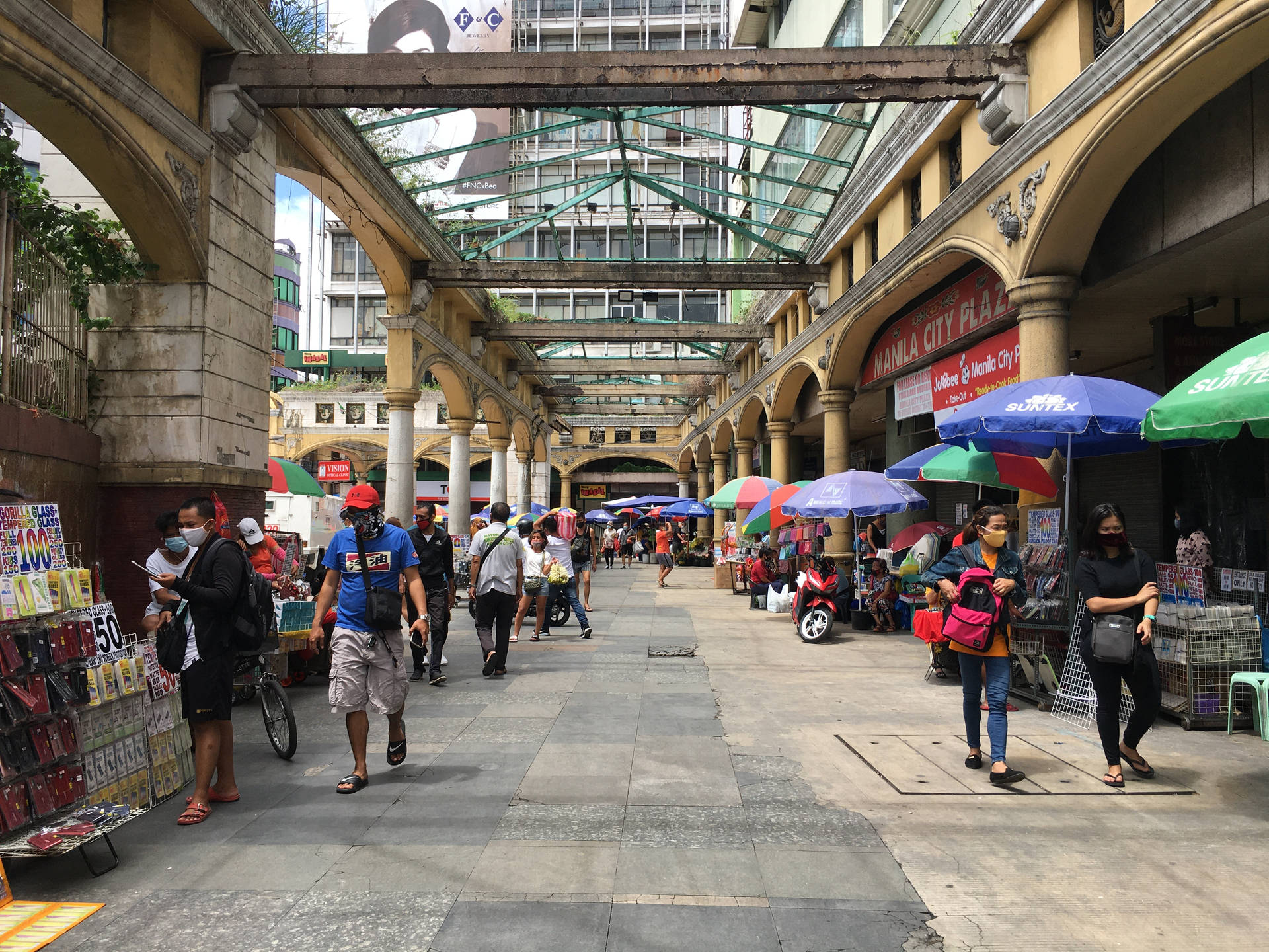 熱鬧的有蓋市場街道，拱門和雨傘下有購物者和攤販。