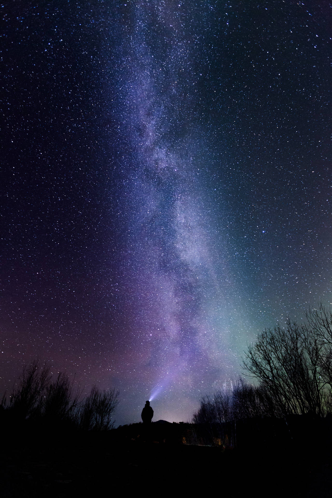 夜晚站在山丘上，銀河系下的人