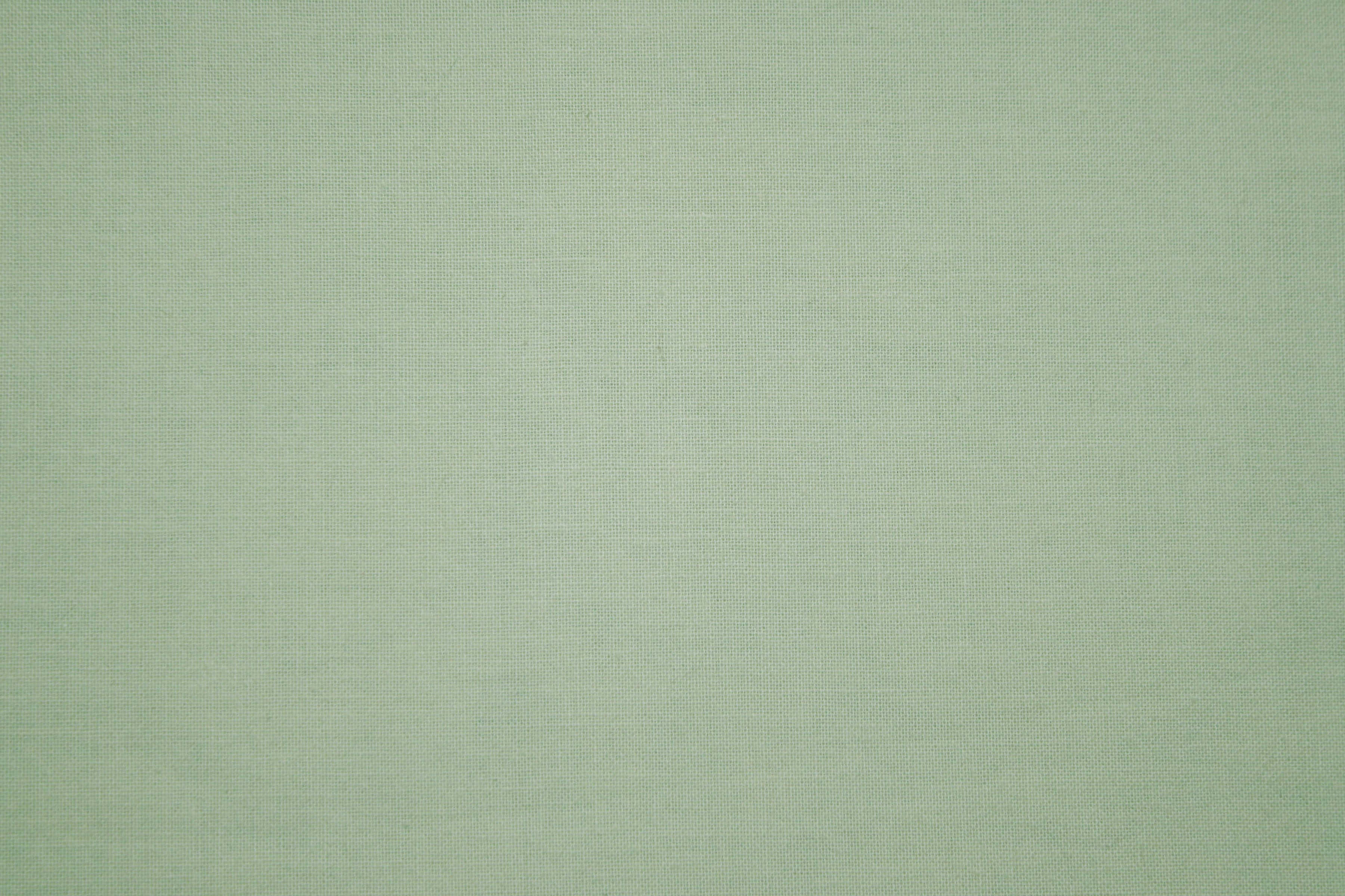 sage green aesthetic 桌布 壁紙 — 均勻光線下光滑淺綠色布料帶有細微編織紋理的近距離特寫。