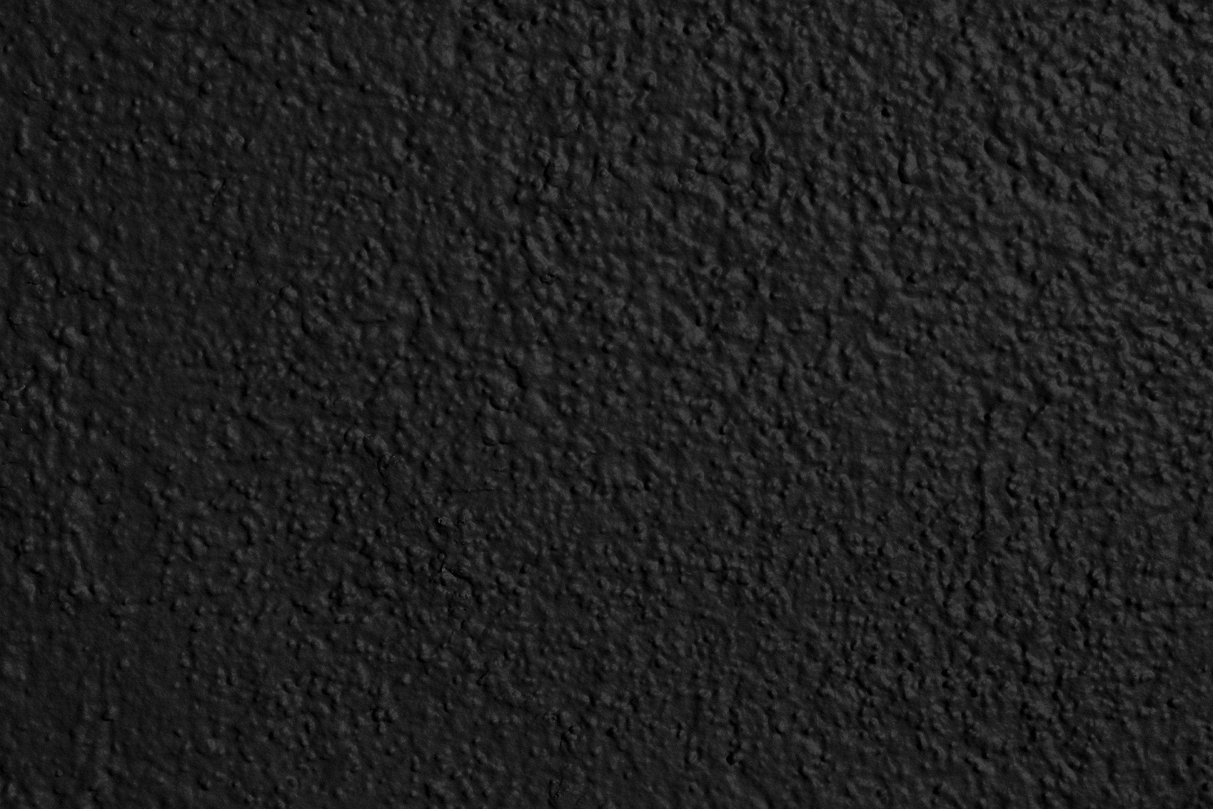 Pain Black And White 桌布 壁紙 — 均勻光線下粗糙黑色灰泥牆的微距特寫，帶有細微紋理變化。