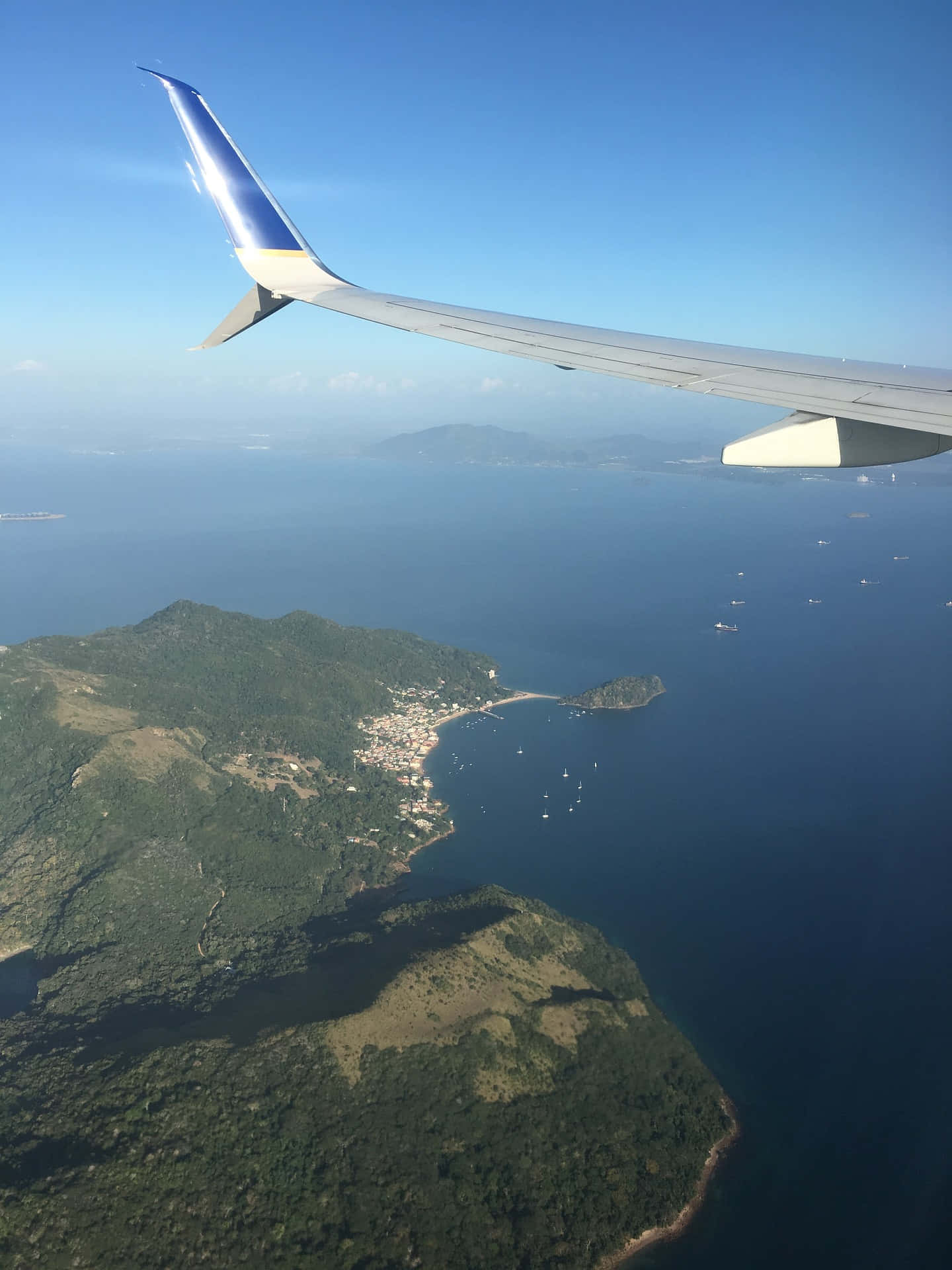 坎昆，天堂在等你 壁紙 — 從飛機窗戶俯瞰的空中景觀，機翼下方是鬱鬱蔥蔥的綠色島嶼、沿海城鎮和深藍色海洋。