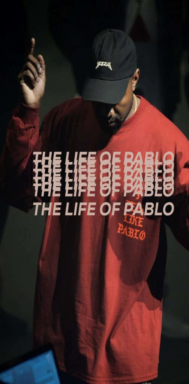 坎耶·威斯特《The Life Of Pablo》專輯封面藝術 壁紙 — 一名身穿紅色「The Life of Pablo」衛衣和黑色鴨舌帽的男子，在戲劇性的舞台燈光下向上做手勢。