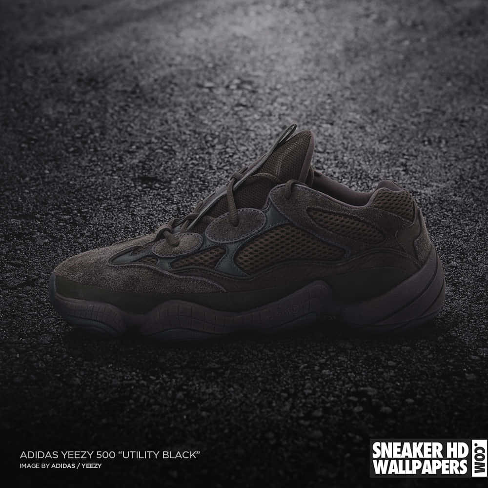 Adidas Yeezy 500 Utility Black運動鞋在濕路面上，聚光燈照射。