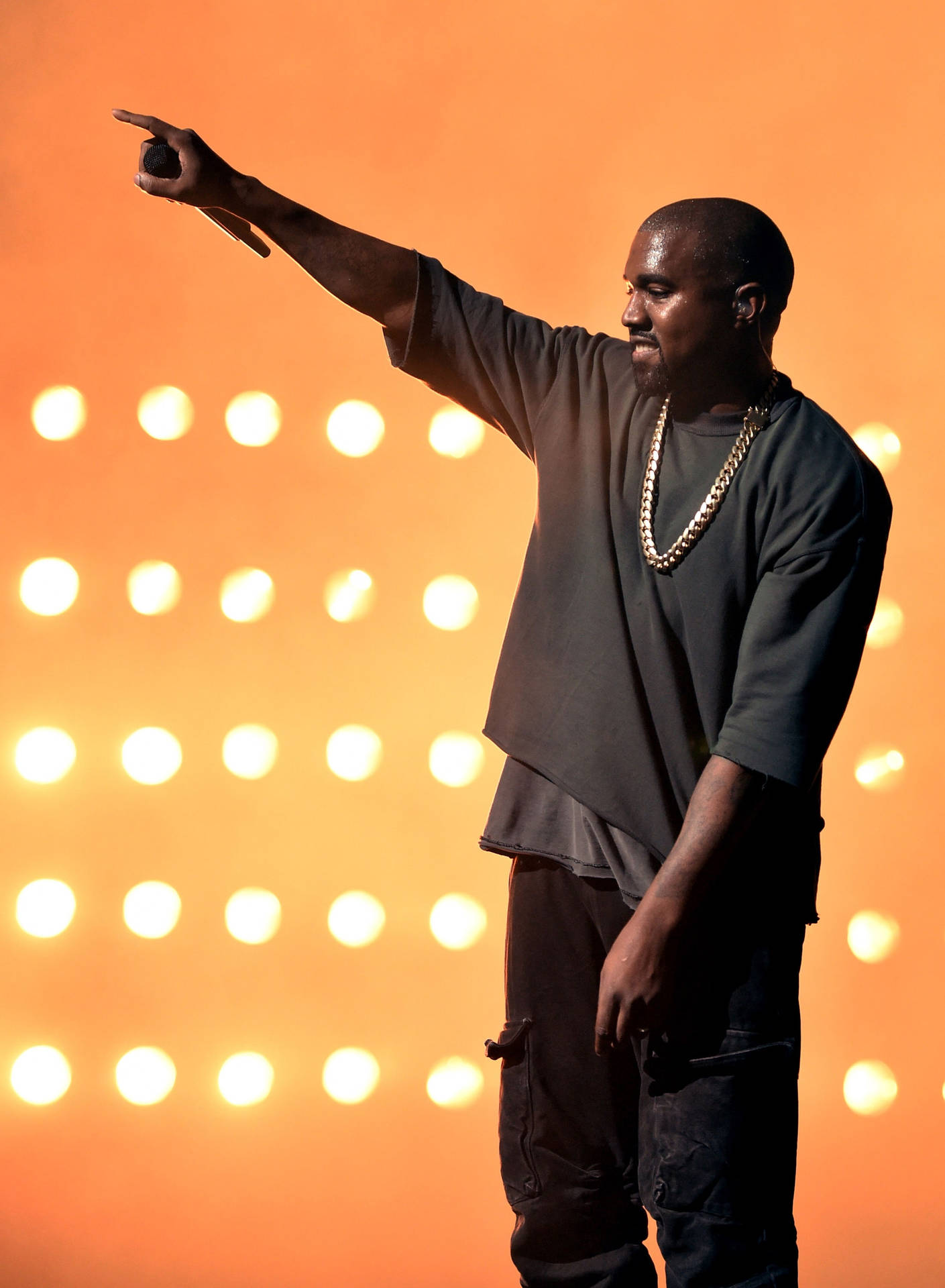 Kanye West 在舞台上指向，背後有發光的燈光。