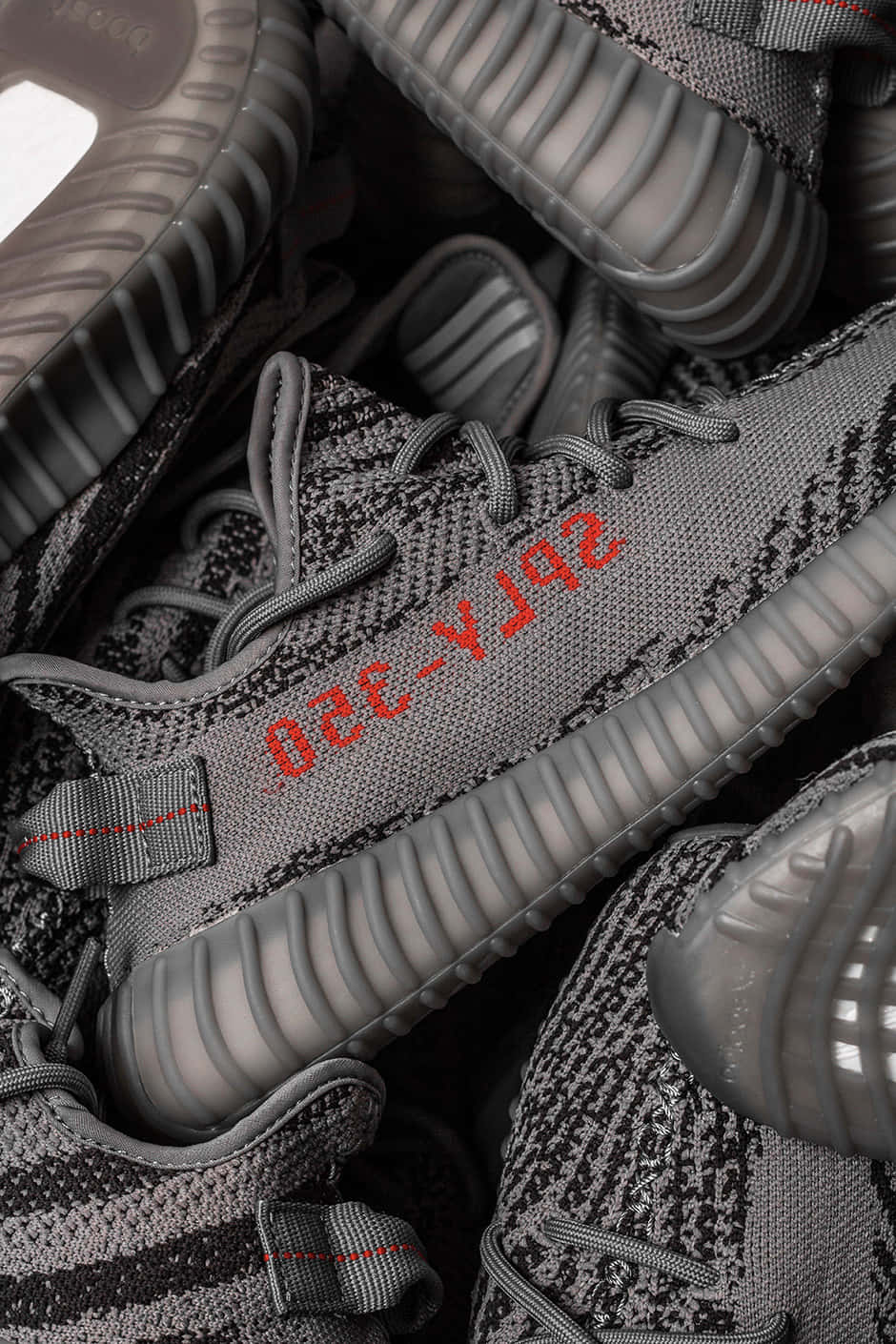 一堆灰色 Yeezy Boost 350 運動鞋，帶有紅色品牌細節。