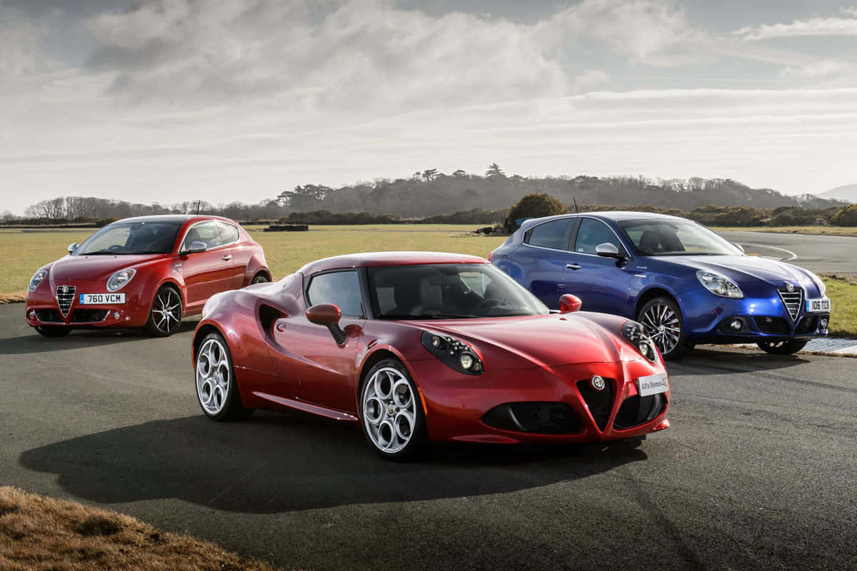 三輛 Alfa Romeo 汽車停在瀝青路上，背景有草地和陰天。