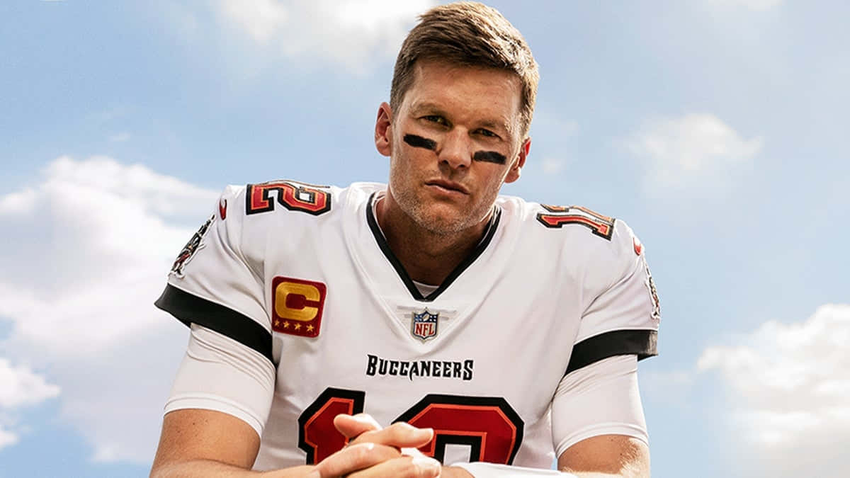 Madden NFL 22 桌布 壁紙 — 坦帕灣海盜隊的四分衛身穿白色球衣，眼部塗有黑色顏料，在藍天白雲下凝視前方。