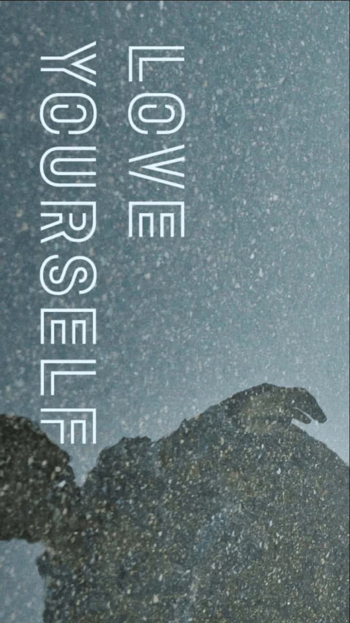 love yourself 桌布 壁紙 — 垂直文字在灰色天空下，以雪山剪影為背景，寫著「愛自己」。