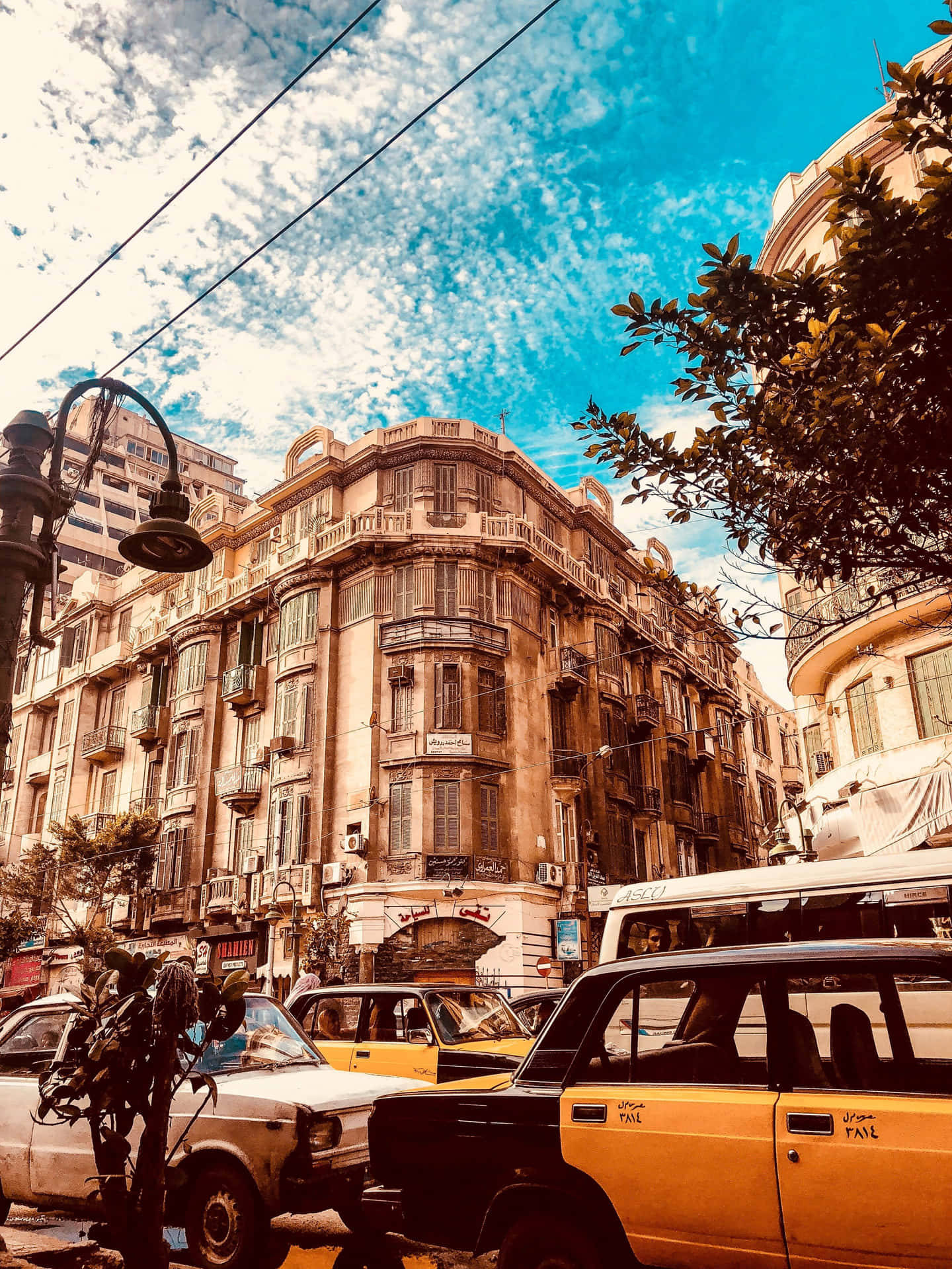 黃色出租車停放在繁忙的城市街道上，周圍是華麗的建築和明亮的藍天。