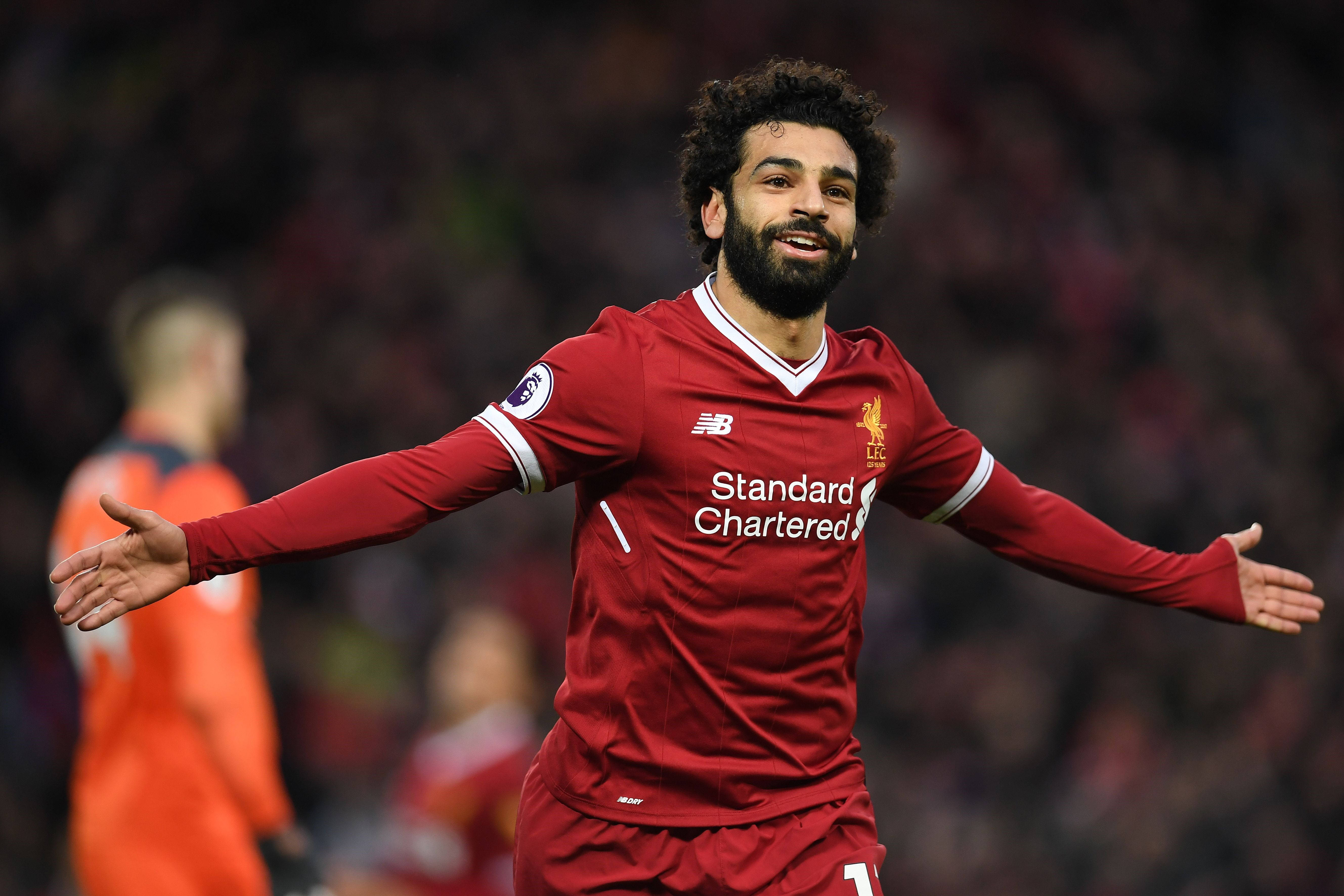 埃及足球員 Mohamed Salah 壁紙 — 一位微笑的足球員身穿紅色利物浦球衣，在球場上張開雙臂慶祝。