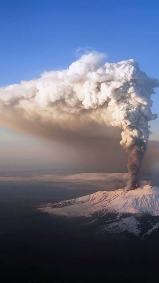 埃特納火山全面爆發災難 壁紙 — 一座白雪覆蓋的火山猛烈噴發，將巨大的火山灰和蒸汽柱噴向晴朗的藍天。