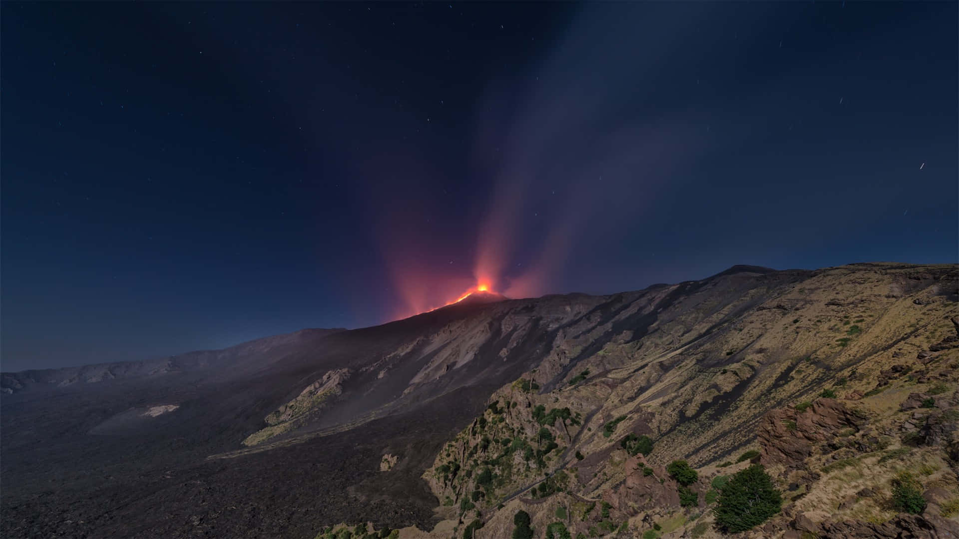 埃特納火山夜景風光 壁紙 — 夜間火山爆發照亮了崎嶇的山脈，在星空下伴隨著發光的熔岩和滾滾濃煙。
