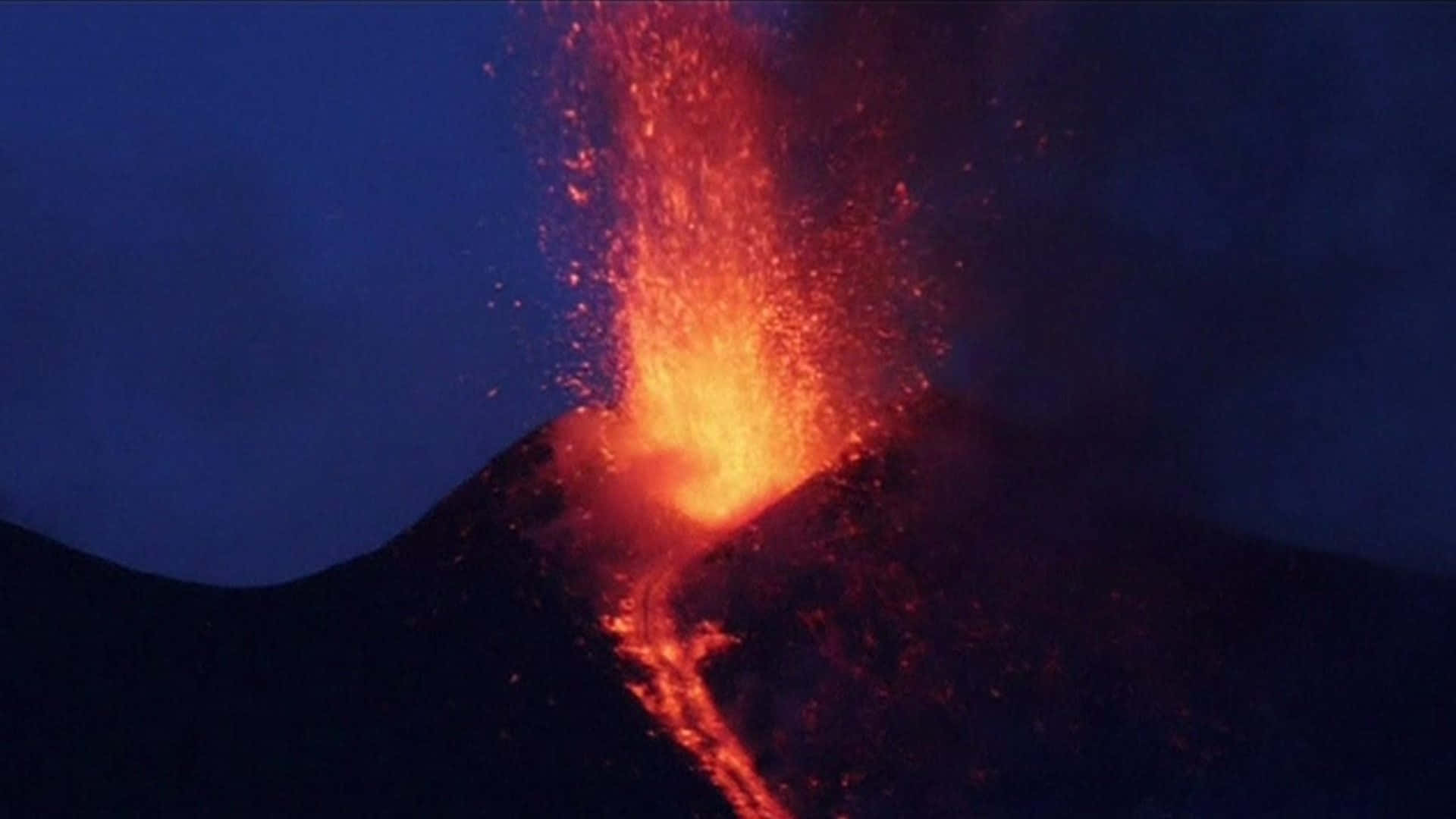 埃特納火山探險隊遭遇火山活動 壁紙 — 火山在夜間猛烈爆發，明亮的橙色熔岩和發光的灰燼在深藍色天空中爆炸。