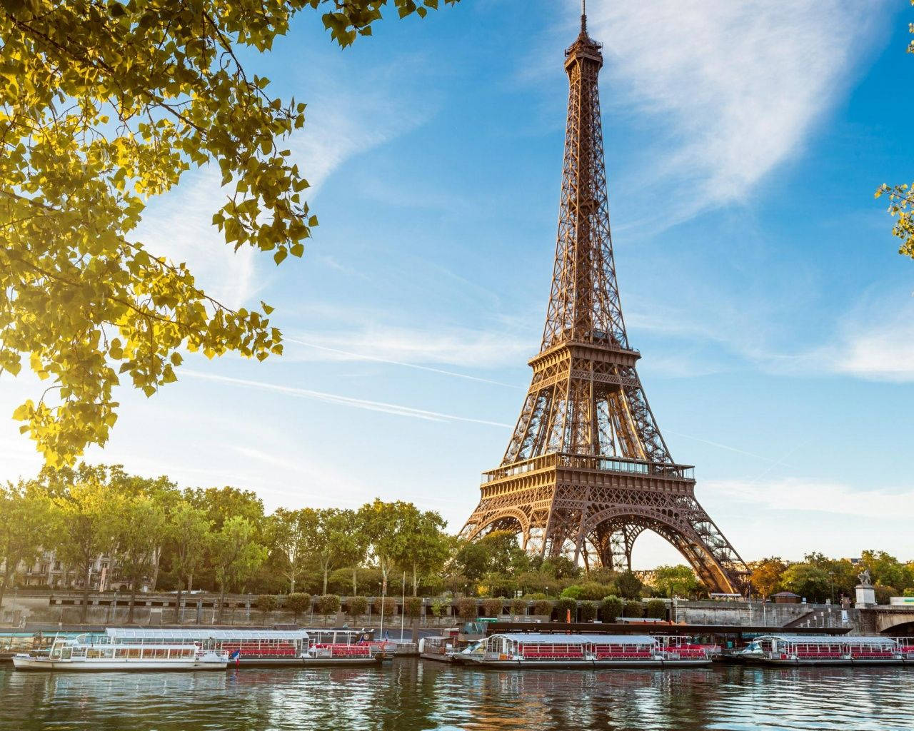 埃菲爾鐵塔與Bassin De La Villette 壁紙 — 艾菲爾鐵塔在清澈的藍天下高聳，金色的樹葉框住場景，船隻在下面的塞納河上漂浮。