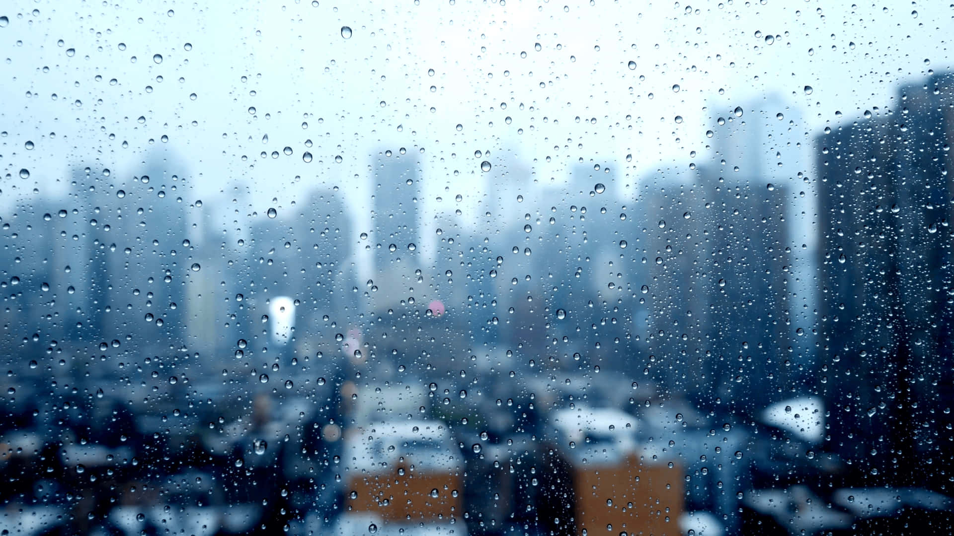 窗戶上的雨滴，俯瞰模糊的城市天際線。