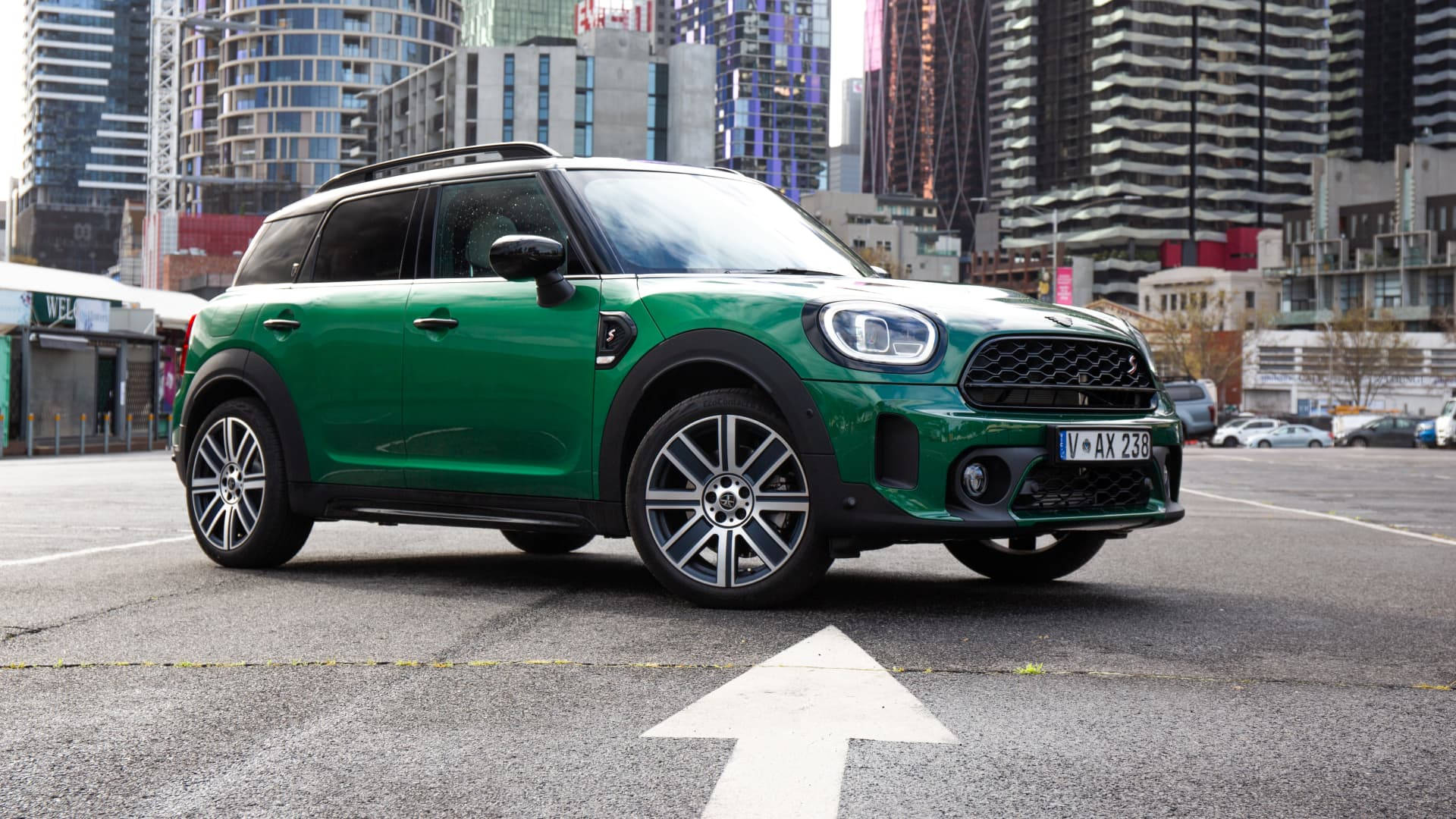 城市中的黑綠色Mini車 壁紙 — 一輛充滿活力的綠色MINI Countryman SUV停泊在城市地塊上，背景是現代摩天大樓。
