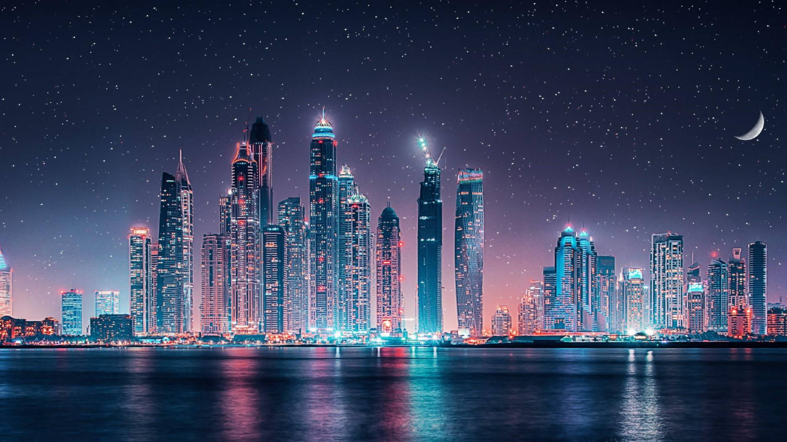 城市夜景 Google Meet 虛擬背景 壁紙 — 在星空和彎月下，高聳的摩天大樓在平靜的水面上反射出鮮豔燈光的迷人夜景。