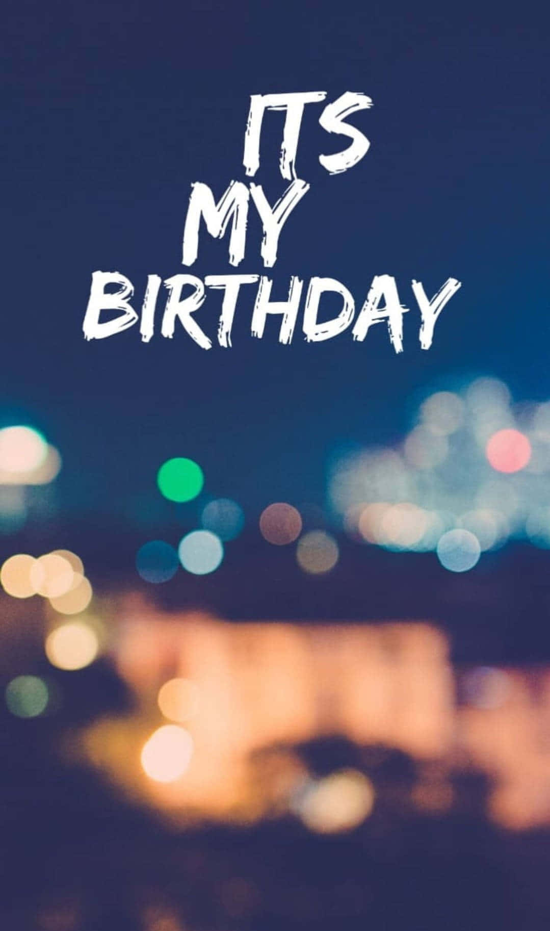 城市夜景：今天是我的生日 壁紙 — 粗體白色文字寫著「its my birthday」，背景是模糊的夜景城市景觀，帶有彩色散景燈光。