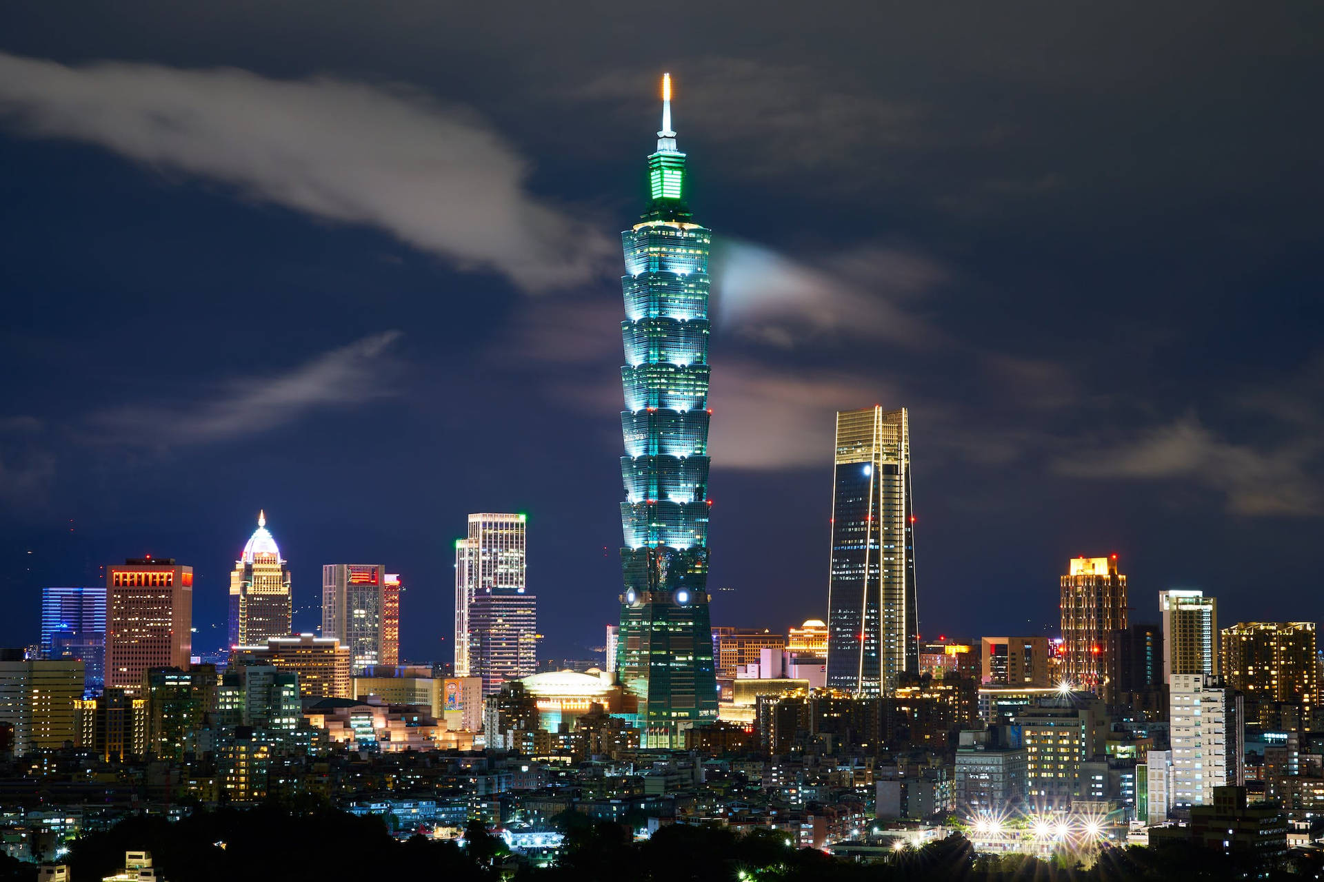 台北101摩天大樓在城市燈光中閃耀著綠色光芒的夜景。