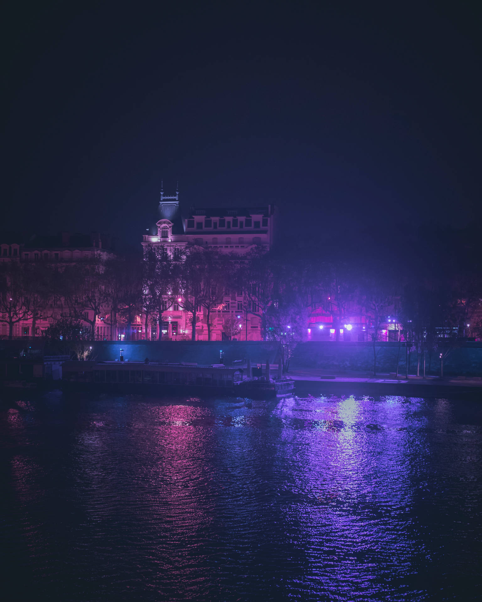 夜晚城市景觀，發光的建築物倒映在水中。