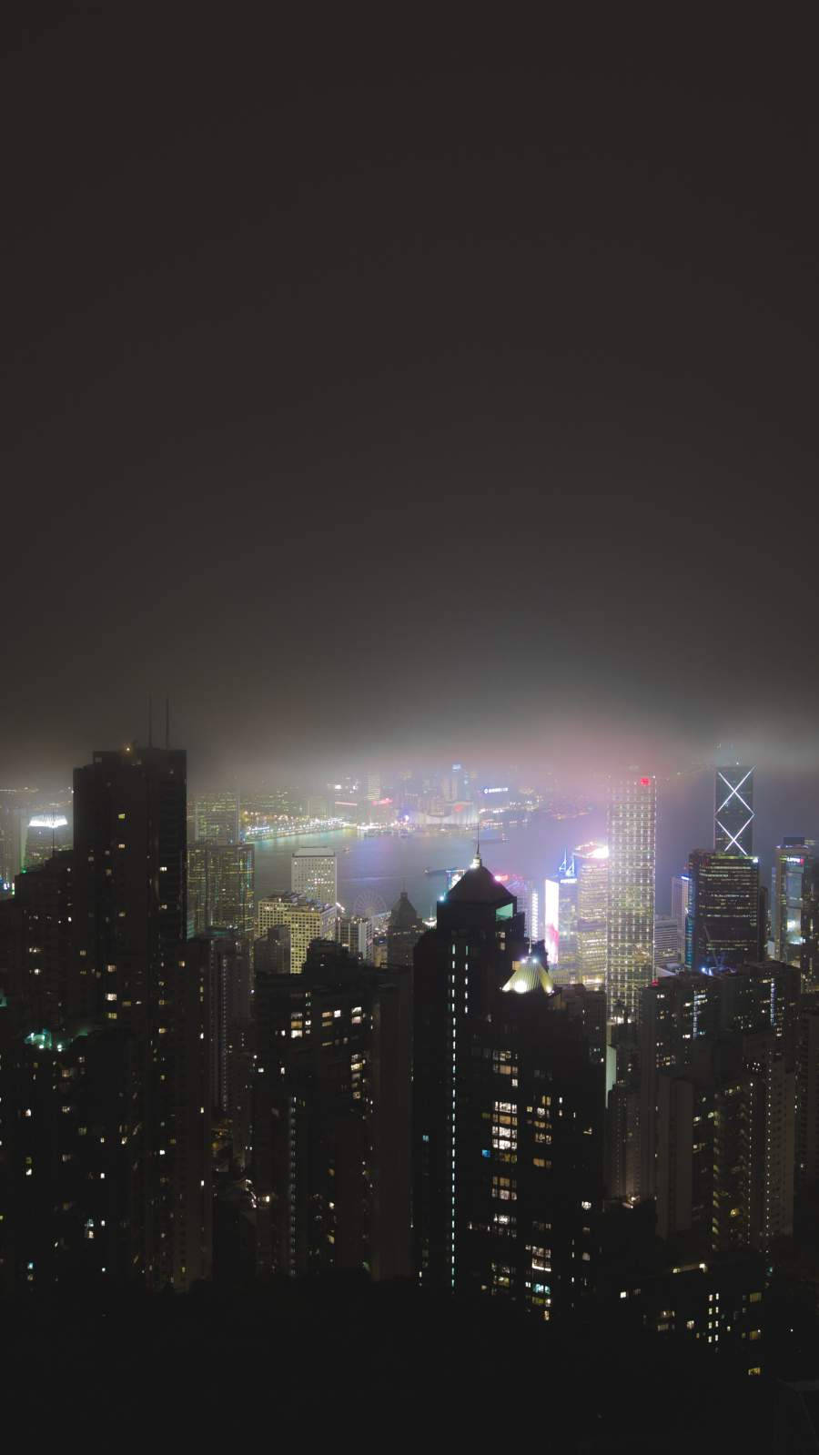 夜晚的城市天際線，燈火通明的建築物和迷濛的氛圍。