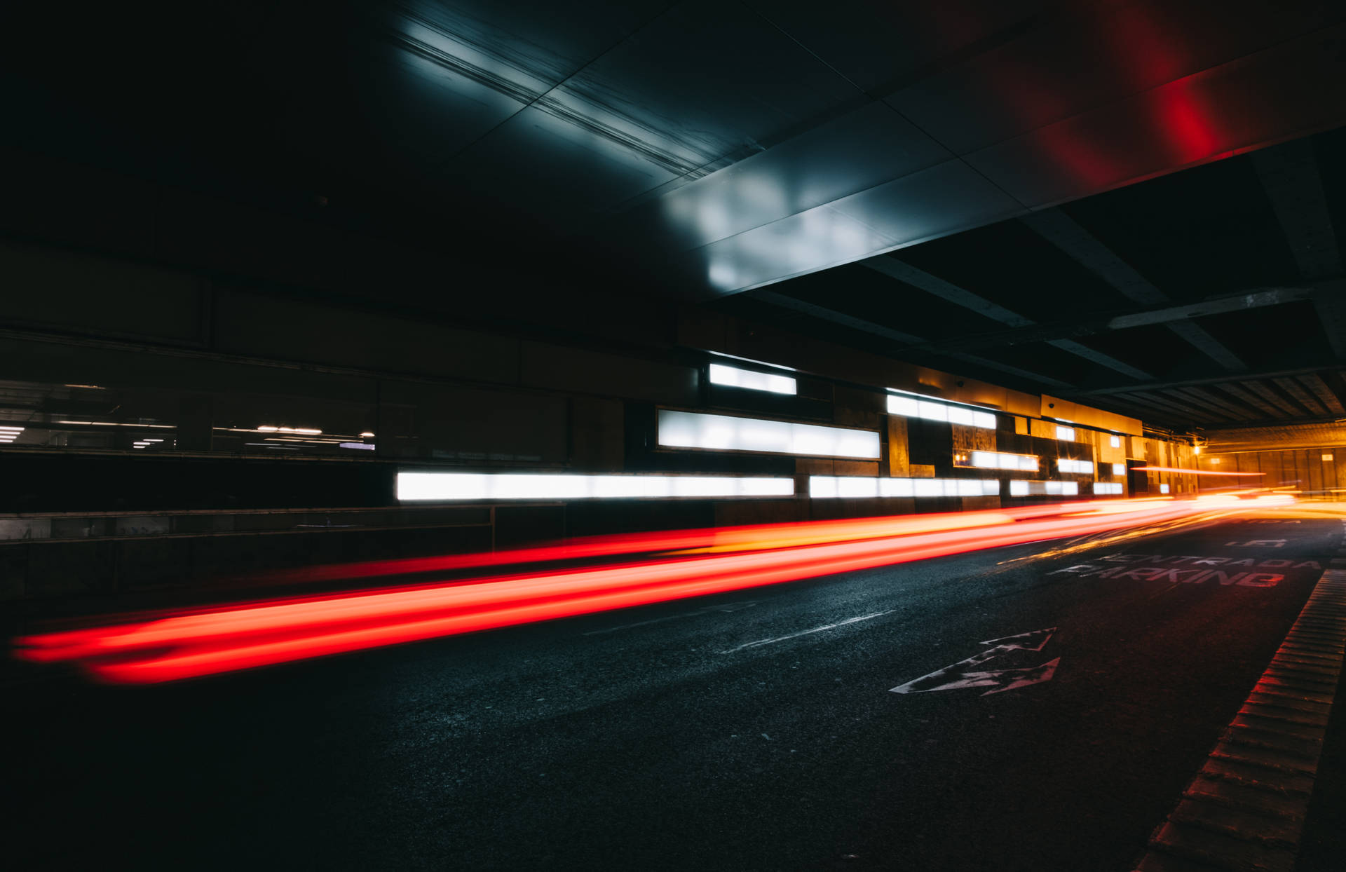 夜晚黑暗的城市隧道地下通道中移動車輛的紅色光條。