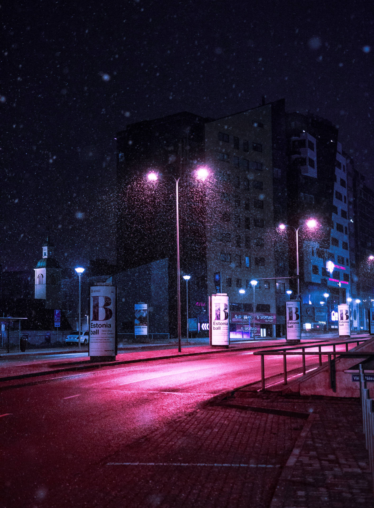 夜晚，在明亮的街燈下，雪落在安靜的城市街道上。