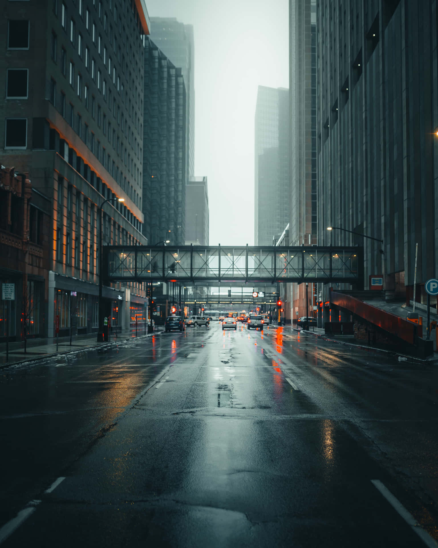 黃昏時分的雨城市街道，高樓大廈和明亮的燈光反射在潮濕的路面上。