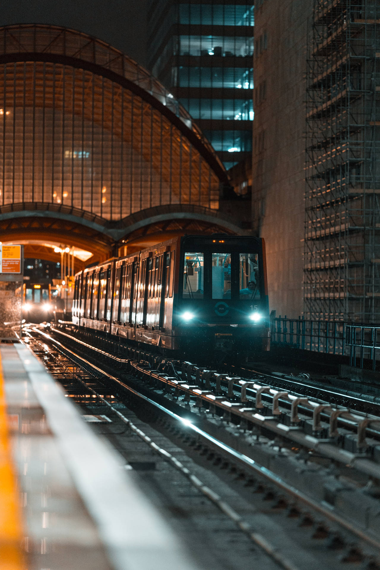 地鐵列車在夜間於城市車站的玻璃天篷下接近。