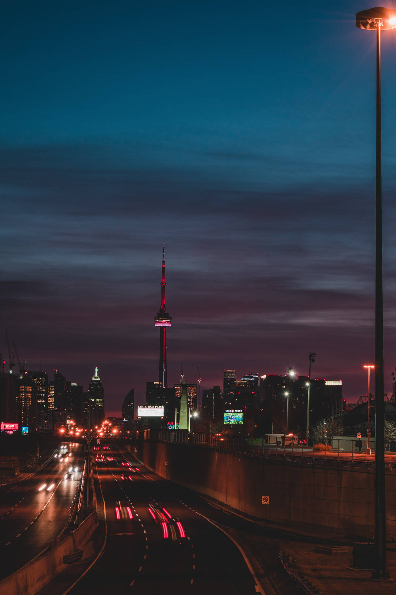 夜晚的城市高速公路，帶有流動的車燈線條和背景中的CN塔。